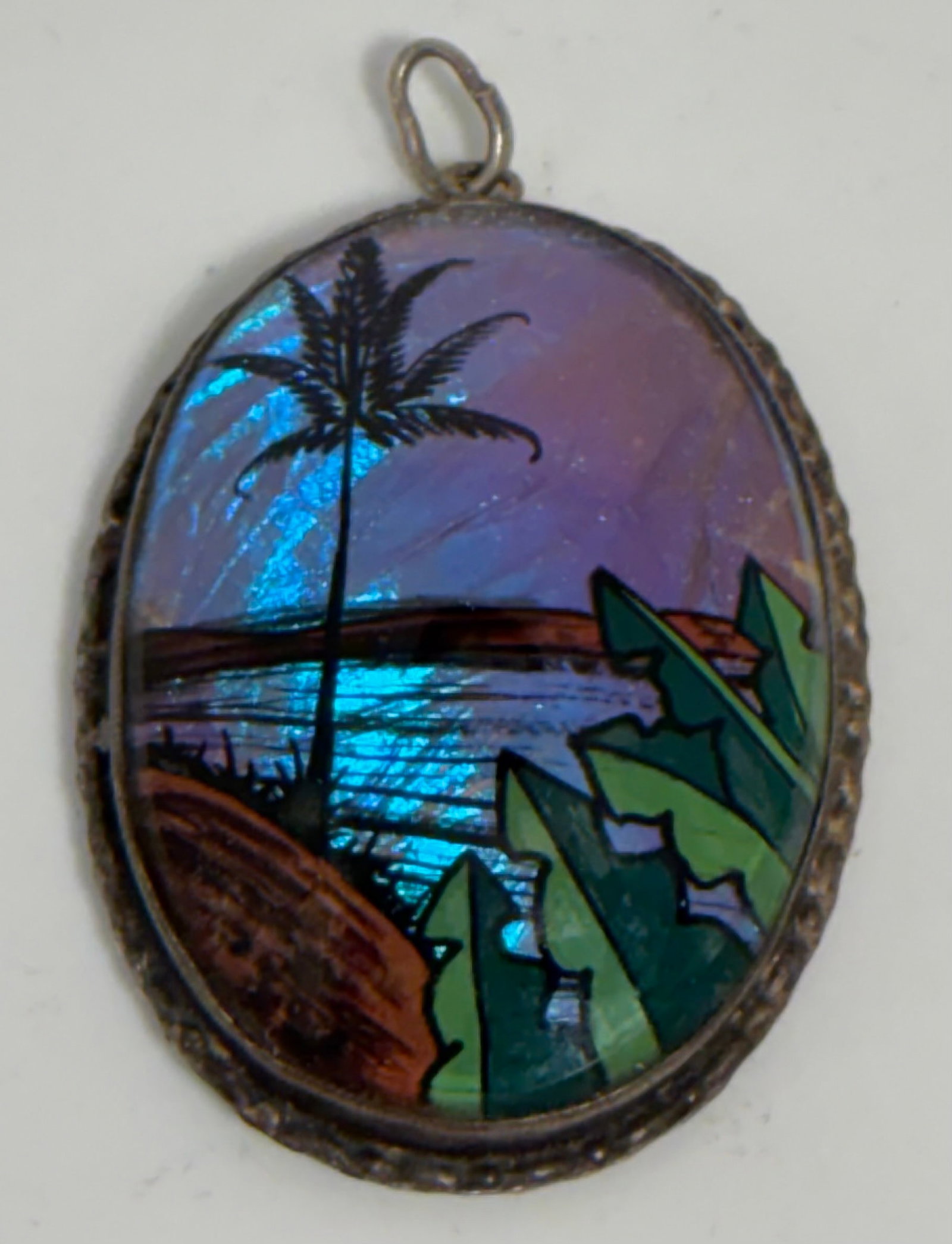 Butterfly Wing Pendant Made in Brazil: A beautiful convex oval pendant featuring blue butterfly wings to represent the sky and water in this tropical scene. The other elements are reverse painted with probably acrylics. Marked on the back 
