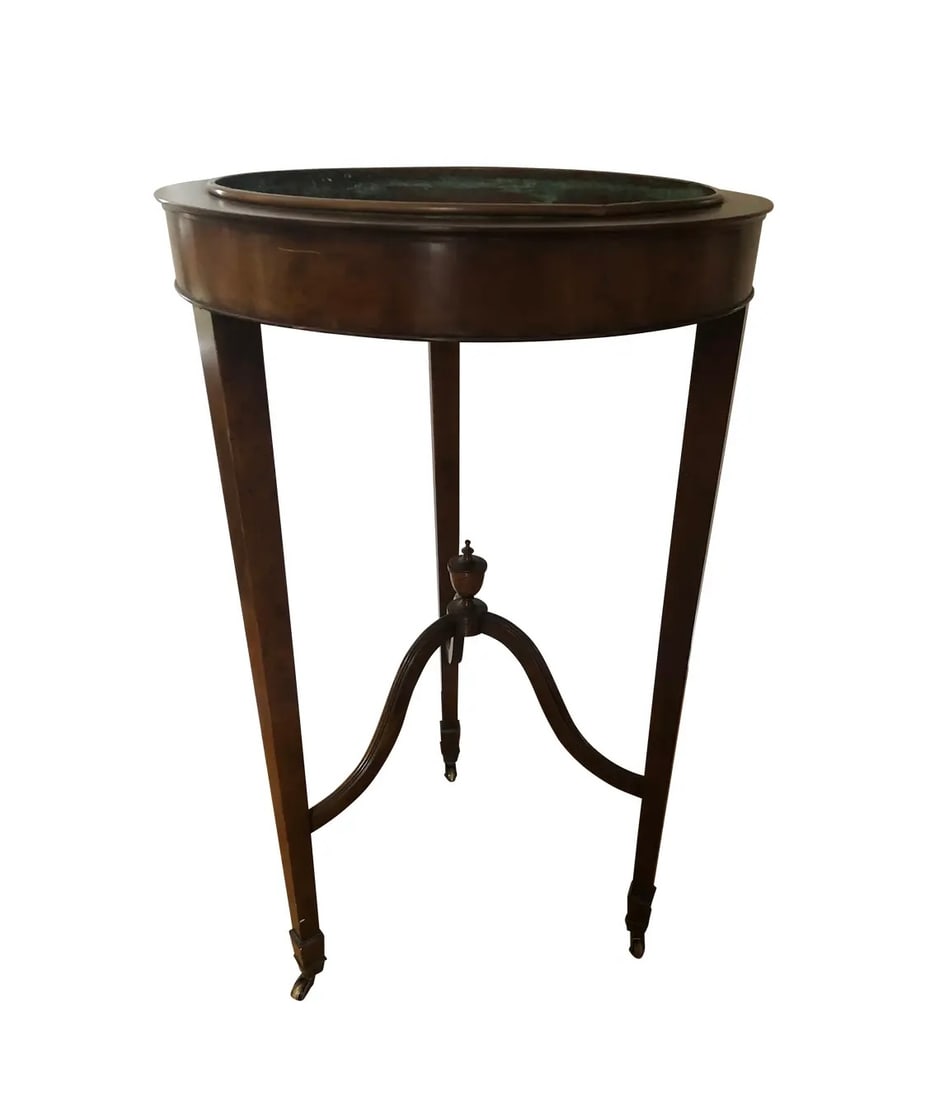 Baker Jardiniere Plant Stand: Baker Co. quality furniture, Jardiniere plant stand traditional Hepplewhite style. This stand is build on three slender legs with caster wheels for mobility. Copper planter inset. Center finial design