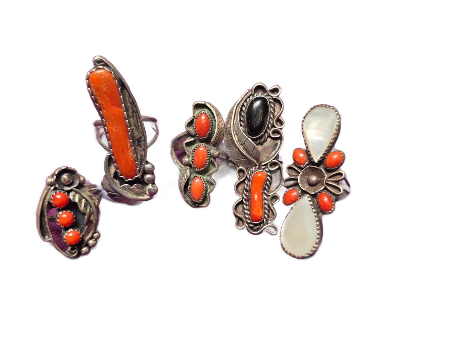 Group of 5 Sterling Silver Coral Rings, One Signed LMF “Navajo Made”: Group of five sterling silver rings set with coral and other stones, including one example signed “Navajo Made” with LMF hallmark.The lot includes a variety of designs, featuring an elongated 