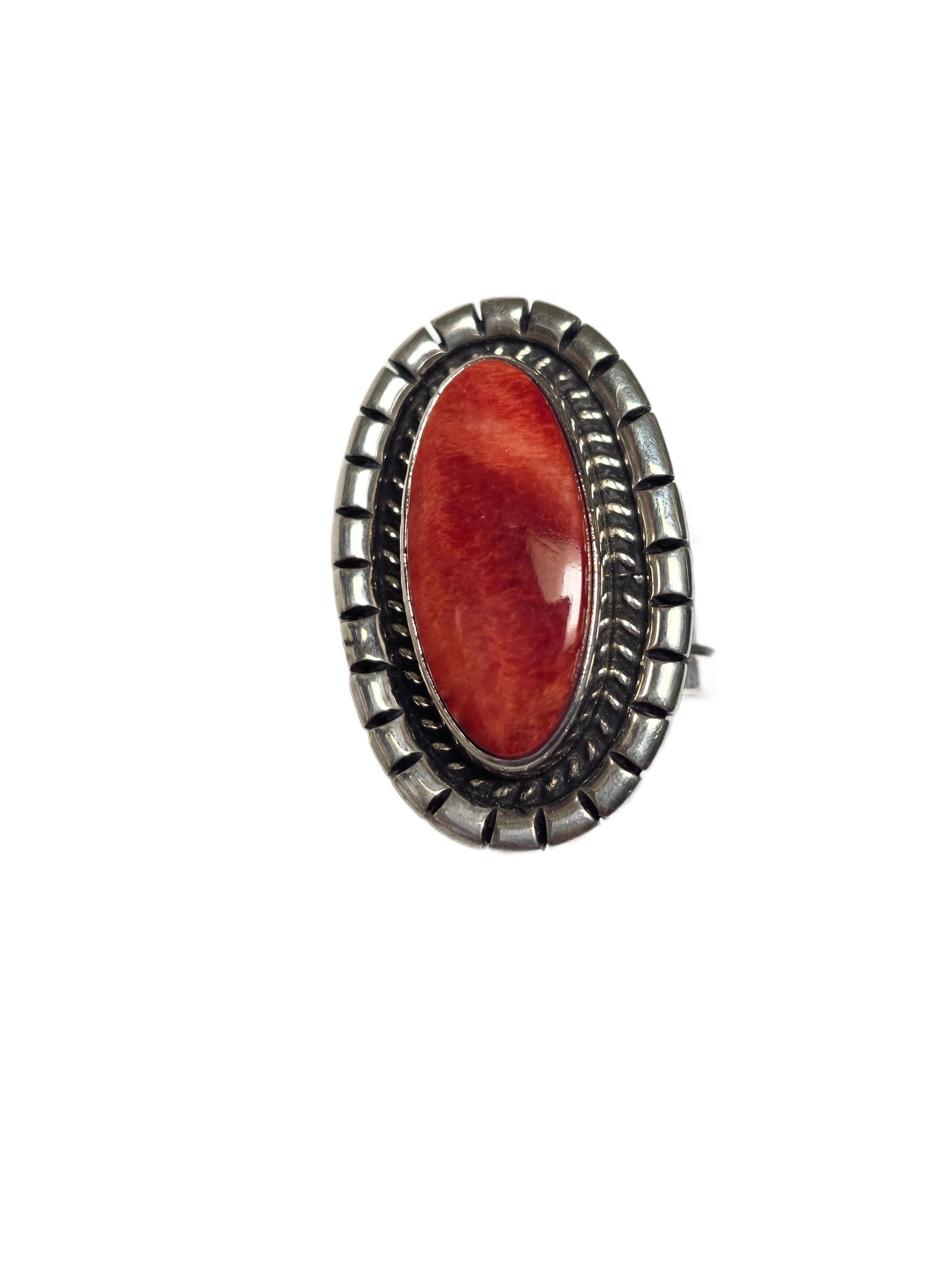 Delvin John (Navajo) Sterling Silver Spiny Oyster Shell Ring: Sterling silver ring by Navajo silversmith Delvin John, set with an elongated oval spiny oyster shell cabochon.The stone displays natural orange to red coloration with visible tonal variation. It is m