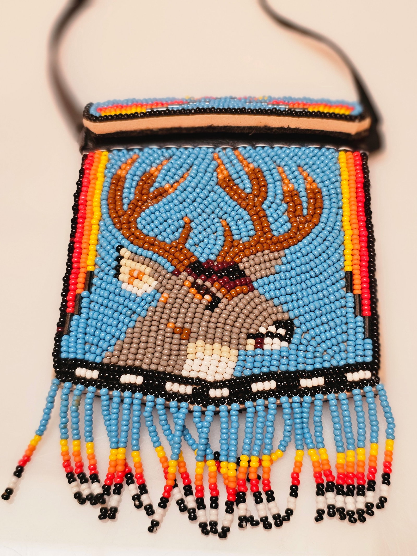 Beaded Deer Motif Medicine Bag–Form Pouch Necklace with Fringe: Beaded pouch-form necklace inspired by traditional medicine bag designs, featuring a deer head motif executed in multicolored glass seed beads.The front panel depicts a stylized deer with antlers set 