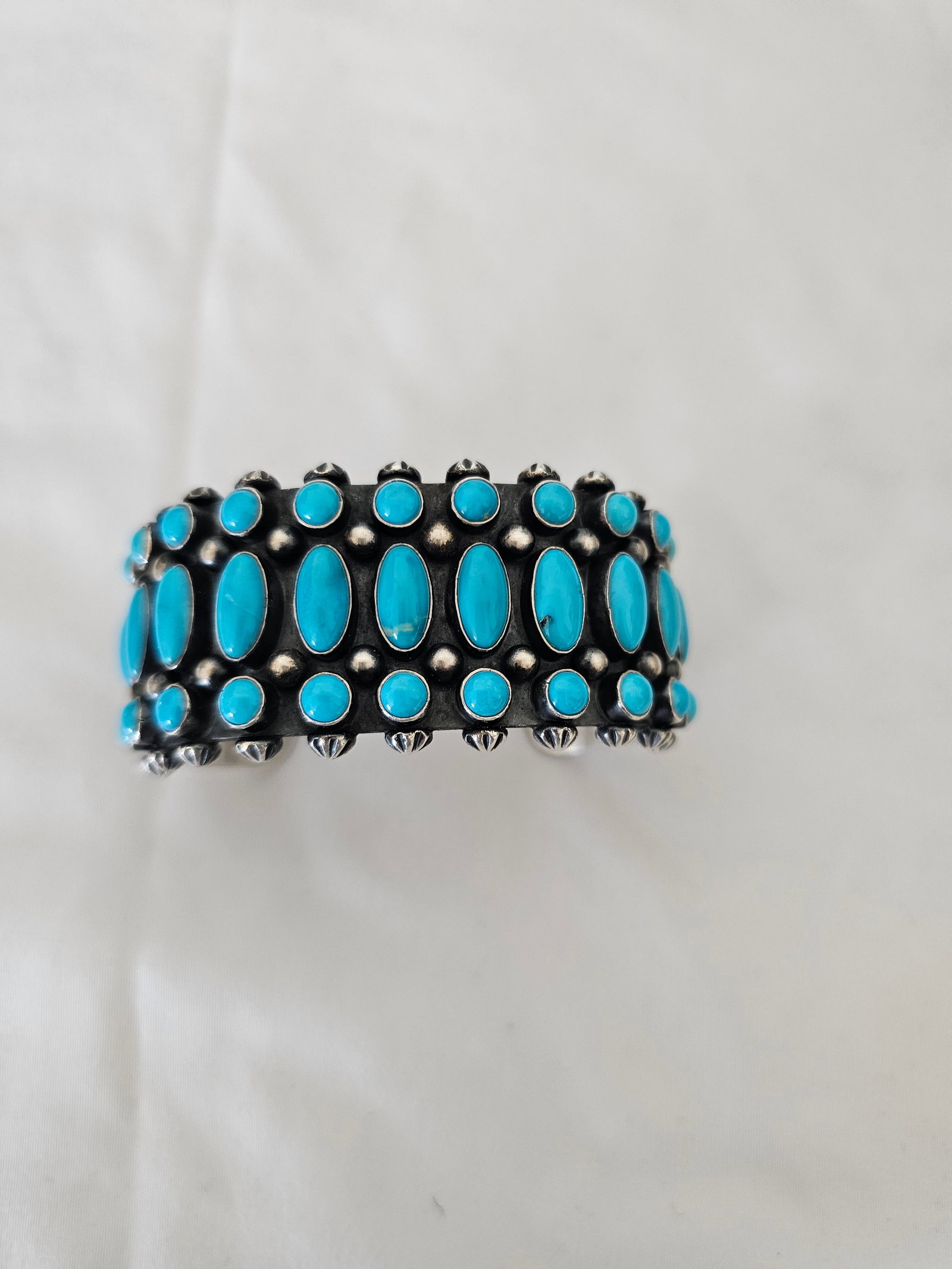 Robert Johnson Navajo Turquoise Cuff 98.14g: Signed Navajo sterling silver cuff bracelet by Robert Johnson, featuring multiple bright turquoise cabochons set across a wide oxidized silver face. The cuff has oval and round turquoise stones, appli