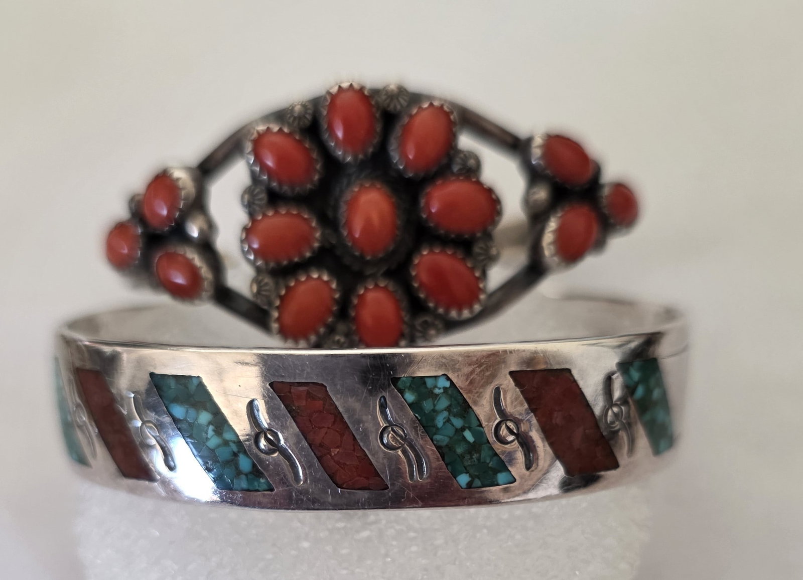 Lot Of Two Coral And Crushed Inlay Sterling Cuffs: Lot of two vintage sterling silver cuffs offering two distinct Southwestern designs in one collector lot. One cuff features crushed-stone inlay with an SD hallmark attributed to William Singer, while 