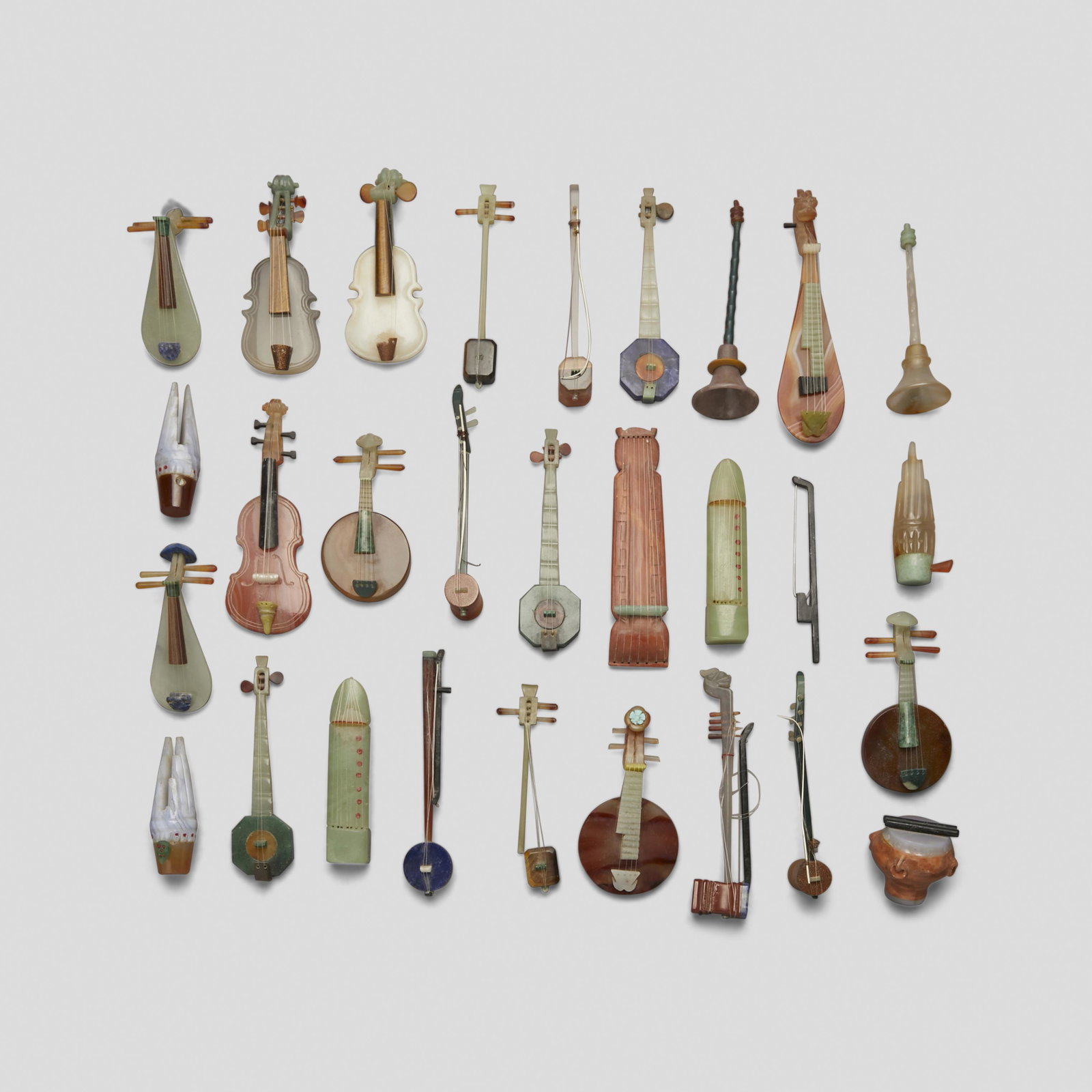 A group of twenty seven miniature hardstone instruments: A group of twenty seven miniature hardstone instruments Including three violins, three bamboo mouth organs (sheng), three qin, one drum, fifteen string instruments, and two bells. 5 1/4in (13.3cm) len