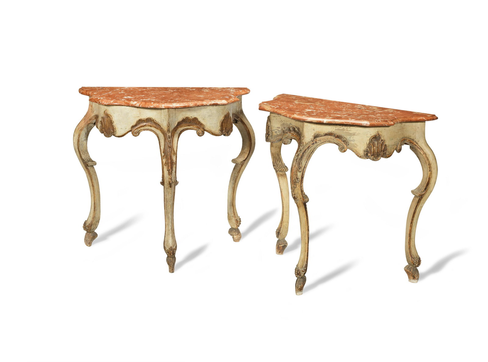 A pair of cream and gilt painted console: A PAIR OF CREAM AND GILT PAINTED CONSOLE TABLES Austrian, 18th century The serpentine shaped marble tops with moulded edges above an undulated shaped frieze with shell motifs on shaped cabriole legs w