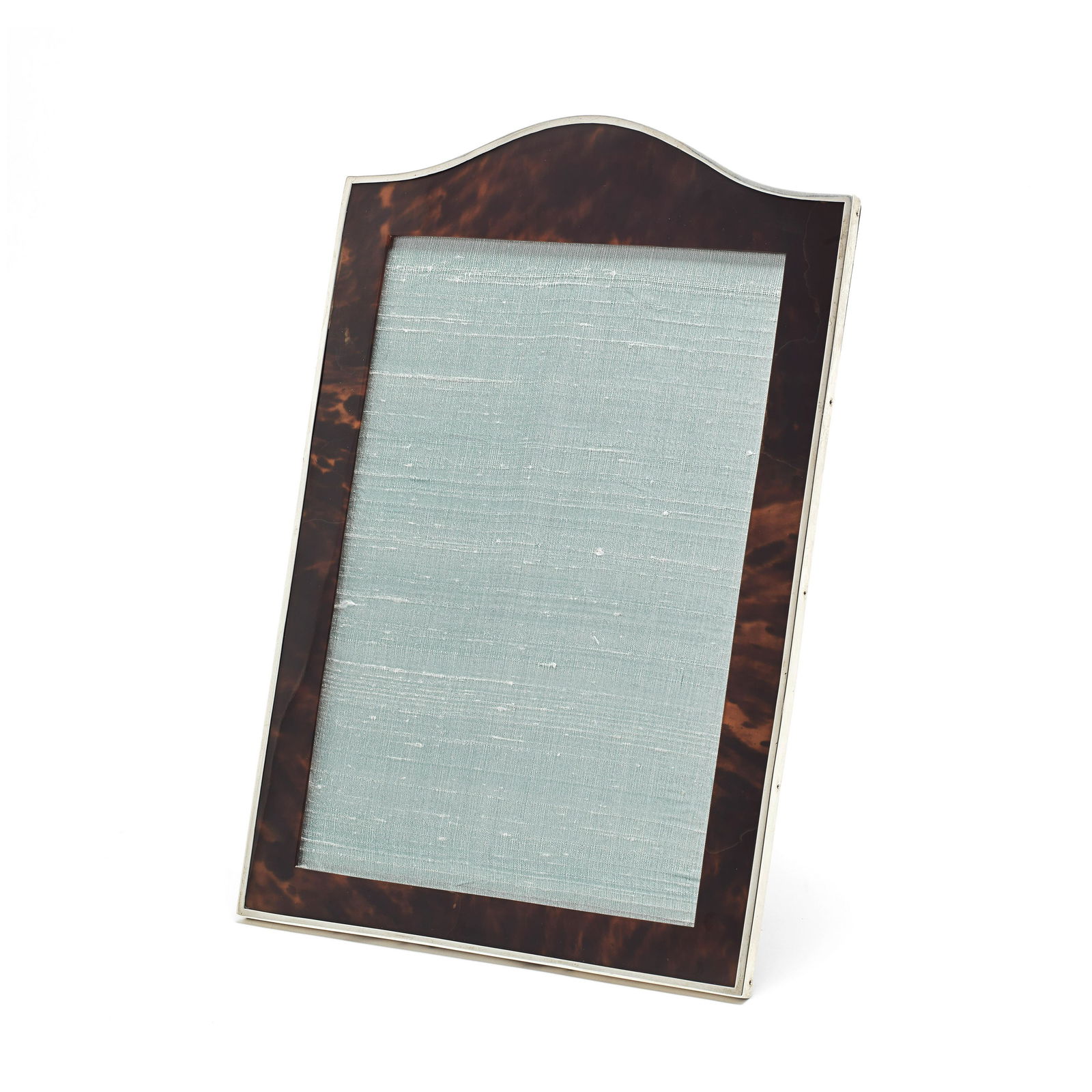A silver-mounted tortoiseshell photograph frame: A silver-mounted tortoiseshell photograph frame Charles and Richard Comyns, London 1917 Upright rectangular with arched top, with tortoiseshell insert and silver mount, with oak easel back, height 37.