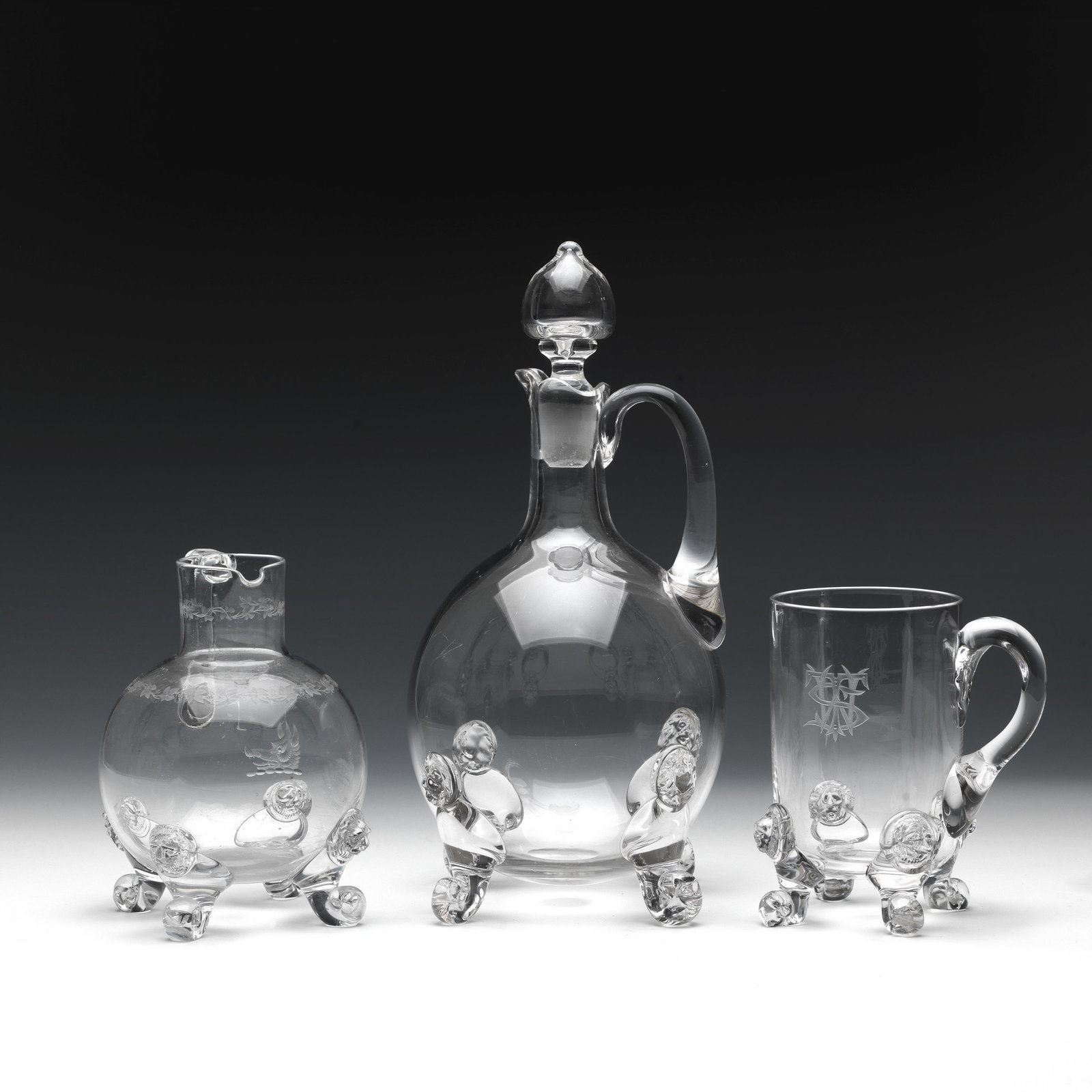 A claret jug from John Ford's Holyrood Glassworks Circa: A claret jug from John Ford's Holyrood Glassworks Circa 1875 Of ovoid form, 26.5cms high, together with a mug engraved with monogram 'WTS' and a jug engraved with the crest of a boar's head and a band