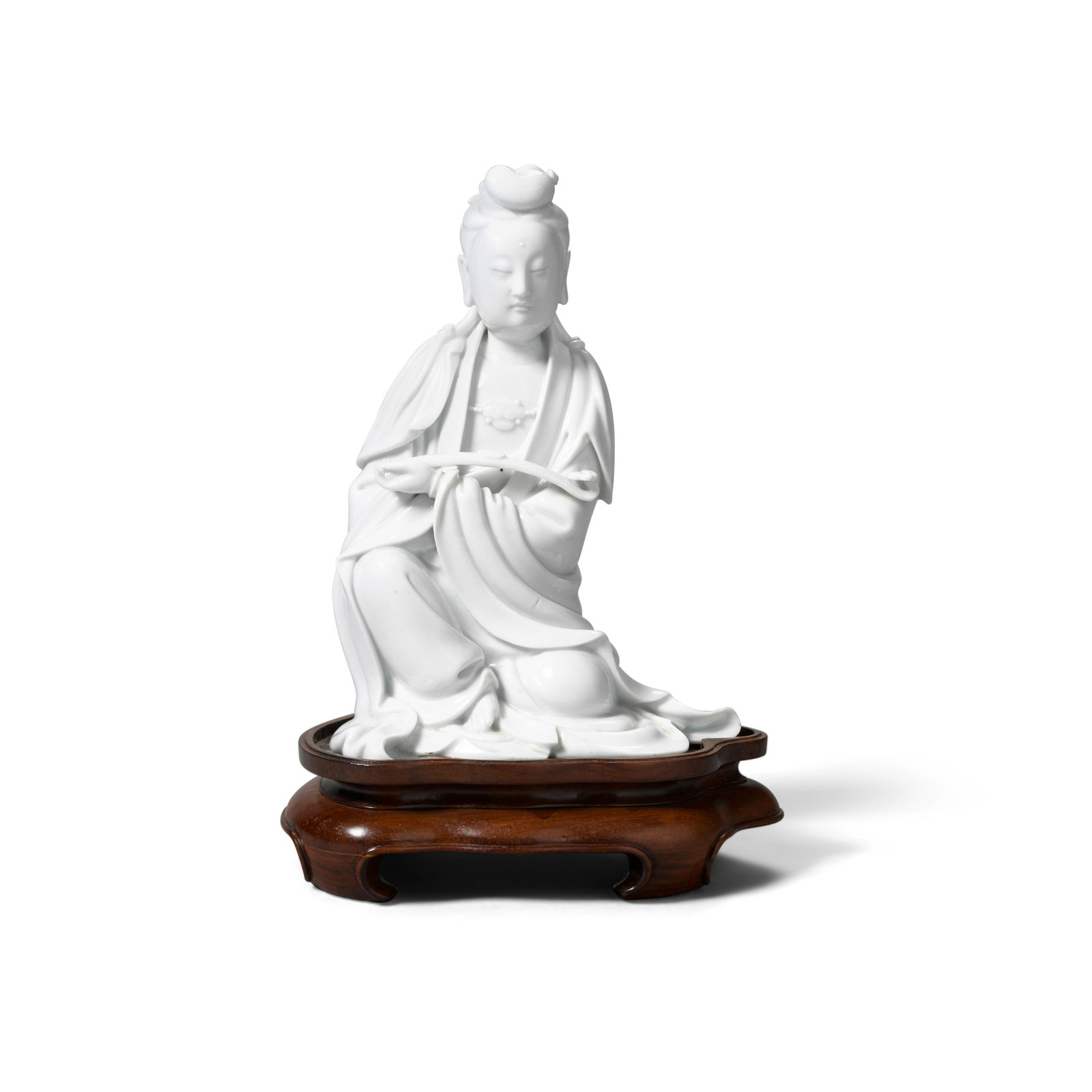 A Dehua figure of Guanyin: A Dehua figure of Guanyin Republic period Seated in 'royal ease' with the proper left arm drawn in front of the chest holding a scepter, the loose robes falling in folds over the body and opening to r