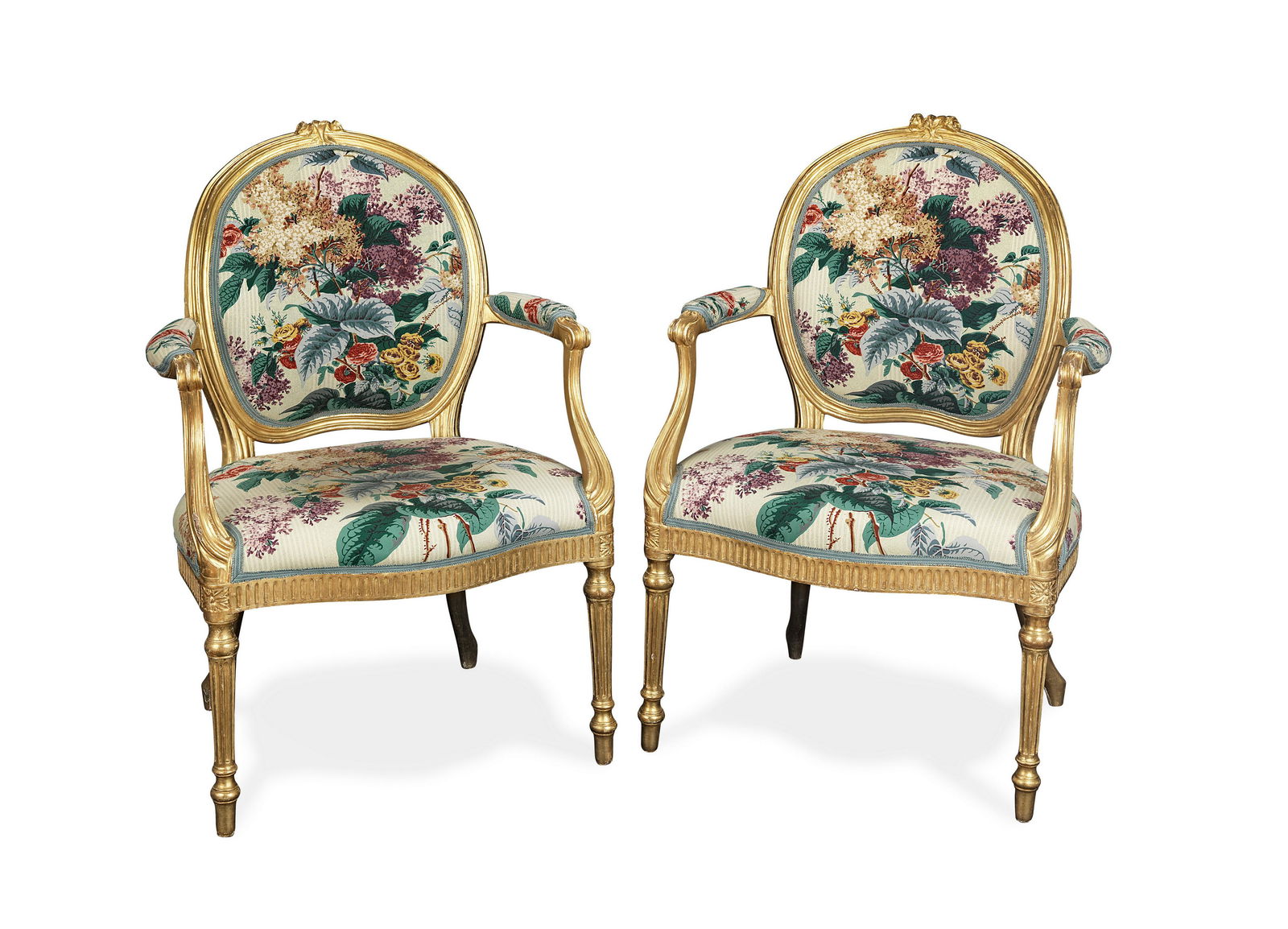 A pair of George III carved giltwood fauteuils In the: A pair of George III carved giltwood fauteuils In the manner of Thomas Chippendale in Louis XVI style With oval backs and scrolled moulded arms on fluted tapering legs, with cramp marks to the undersi