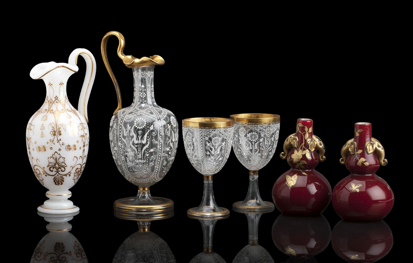 A PAIR OF CASED STOURBRIDGE GLASS VASES: A PAIR OF CASED STOURBRIDGE GLASS VASES Probably Thomas Webb and Son Each formed as a sang de boeuf double gourd vase with elephant handles, embellished with gilt foliage, 15.5cm high, a Stourbridge e