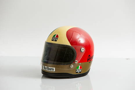 An AGV helmet, by repute worn by Giacomo Agostini, believed 1970's: An AGV helmet, by repute worn by Giacomo Agostini, believed 1970'spainted in patriotic Italian colours with gold neck band, applied with Ago, AGV and Marlboro stickers, fitted with clear Bob Heath