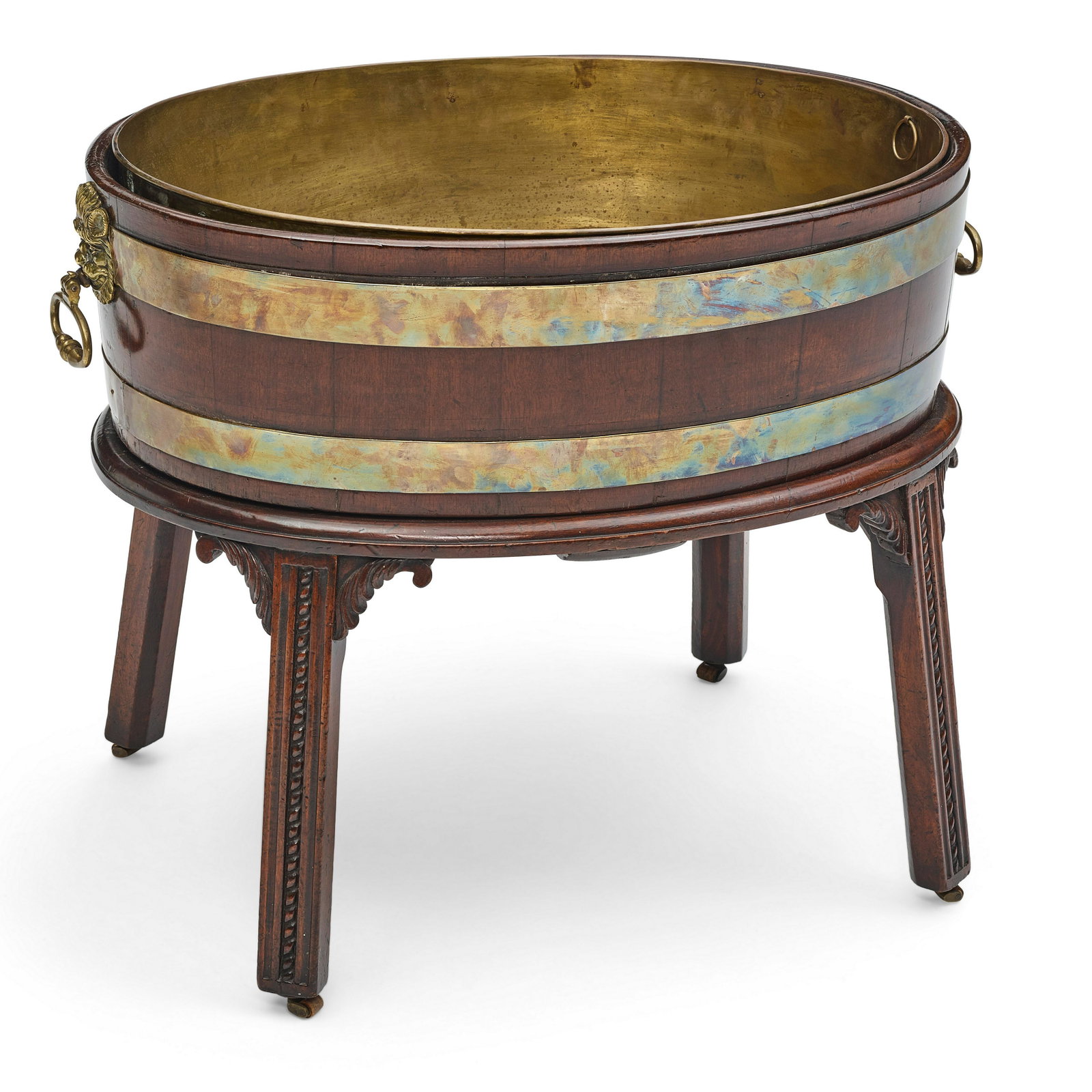 A GEORGE III BRASS BOUND MAHOGANY OVAL WINE COOLERAttributed to Gillows, Lancaster, circa 1770: A GEORGE III BRASS BOUND MAHOGANY OVAL WINE COOLER Attributed to Gillows, Lancaster, circa 1770 On stand. height 22in (56cm); greatest width 27in (68.6cm); depth 19 3/4in (50.2cm) Footnotes: The lion'