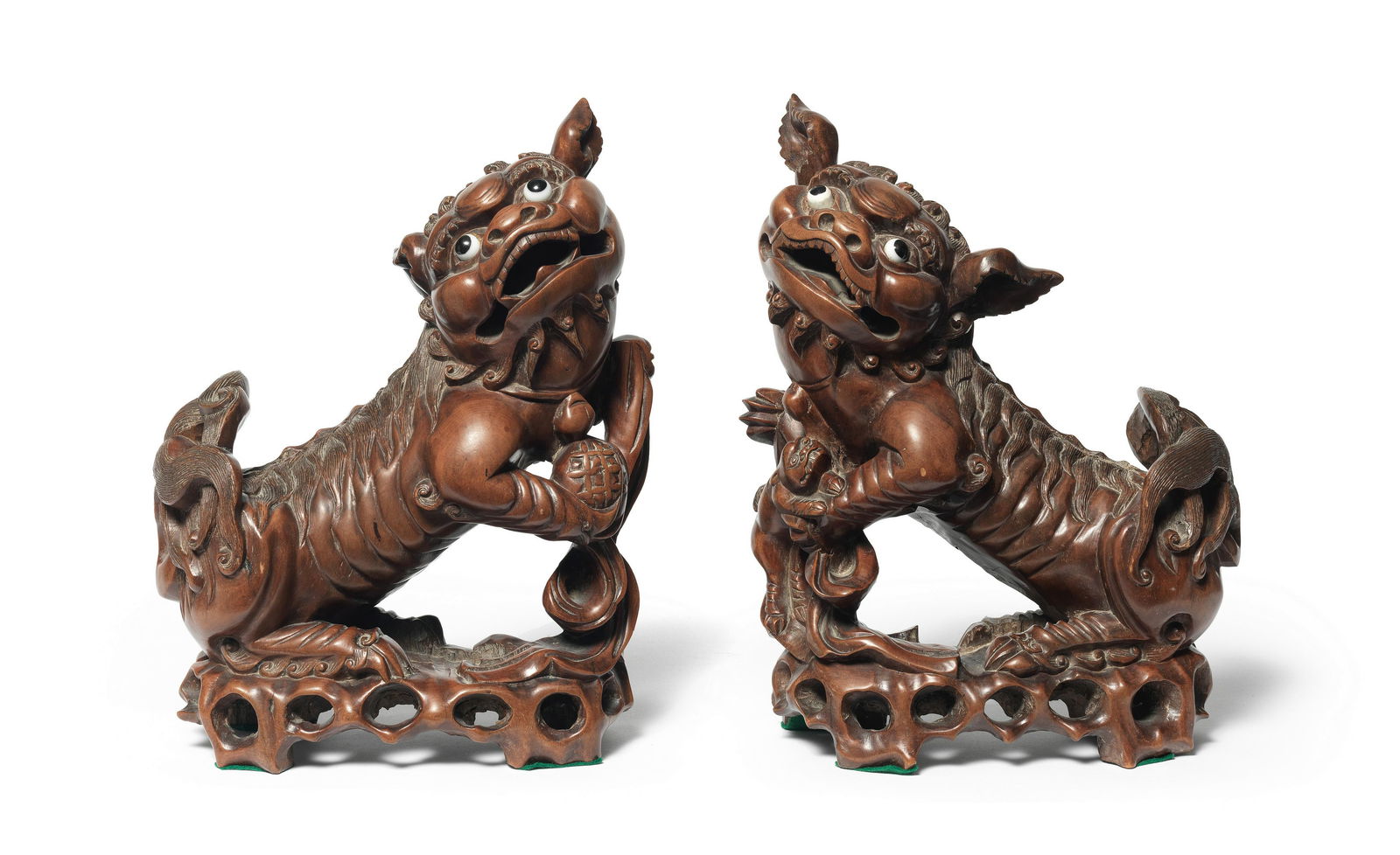 A PAIR OF CARVED WOOD BUDDHIST LIONS Republic Period: A PAIR OF CARVED WOOD BUDDHIST LIONS Republic Period Each modelled as male and female beasts seated on their haunches with wide bulging eyes and wide gaping mouths, the neck, mane and tail finely inci