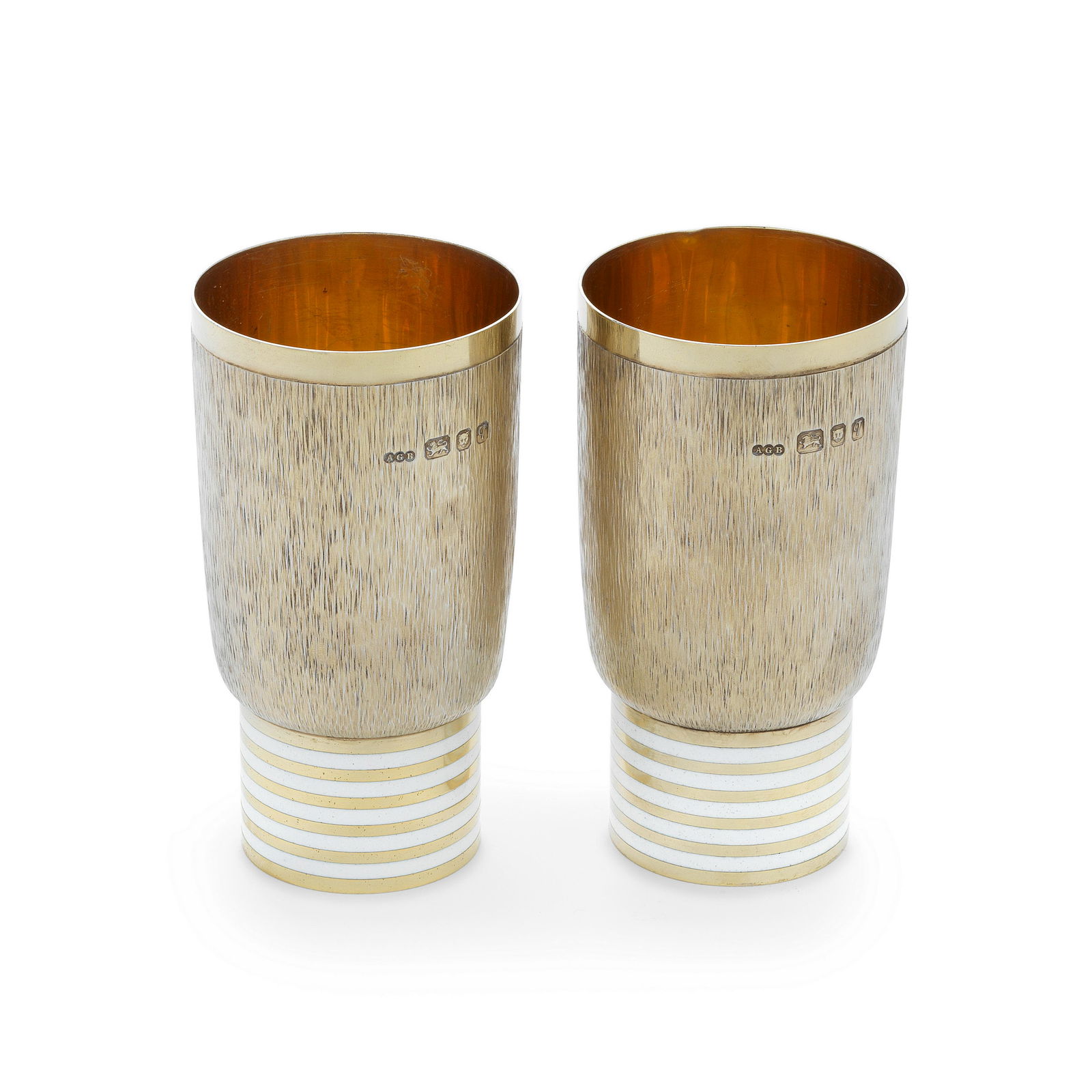 GERALD BENNEY: a pair of silver-gilt and enamelled beakers London 1971 (2): GERALD BENNEY: a pair of silver-gilt and enamelled beakers London 1971 Polished rim above the textured sides, polished cylindrical bases inset with five white enamelled bands, height 11cm, weight 11.3