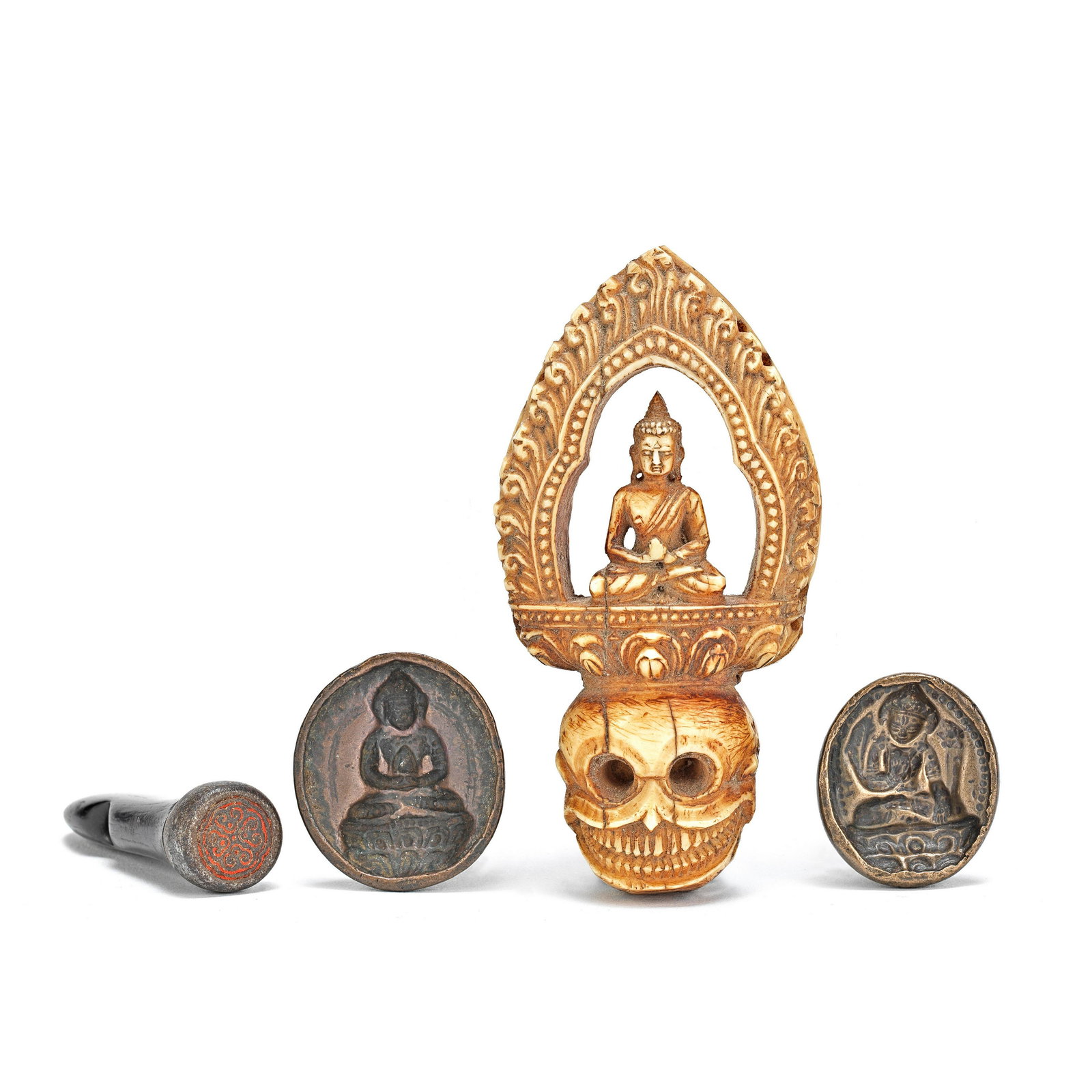 A CARVED BONE 'BUDDHA AND SKULL' PENDANT AND TSHA TSHA MOULDS AND SEAL Tibet, 15th and 17th cent...: A CARVED BONE 'BUDDHA AND SKULL' PENDANT AND TSHA TSHA MOULDS AND SEAL Tibet, 15th and 17th century Comprising: a bone carved pendant with pierced decoration of a Shakyamuni Buddha on a lotus pedestal