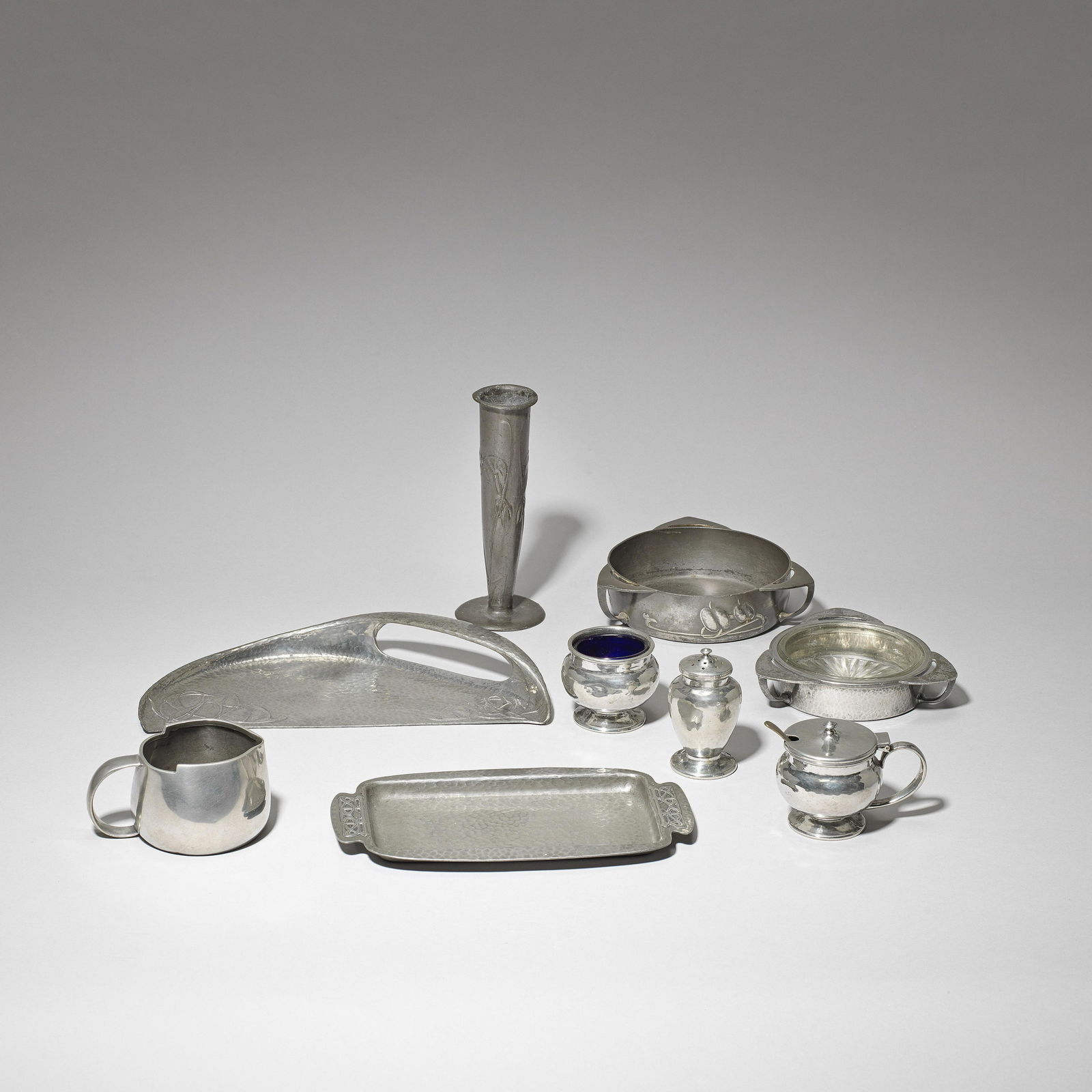 Liberty & Co. Nine 'Tudric' tablewares, circa 1905: Liberty & Co. Nine 'Tudric' tablewares, circa 1905 Pewter. Comprising; rectangular tray, three-piece cruet, two butter dishes (one with glass liner), milk jug, flower vase and crumb scoop; Latter desi