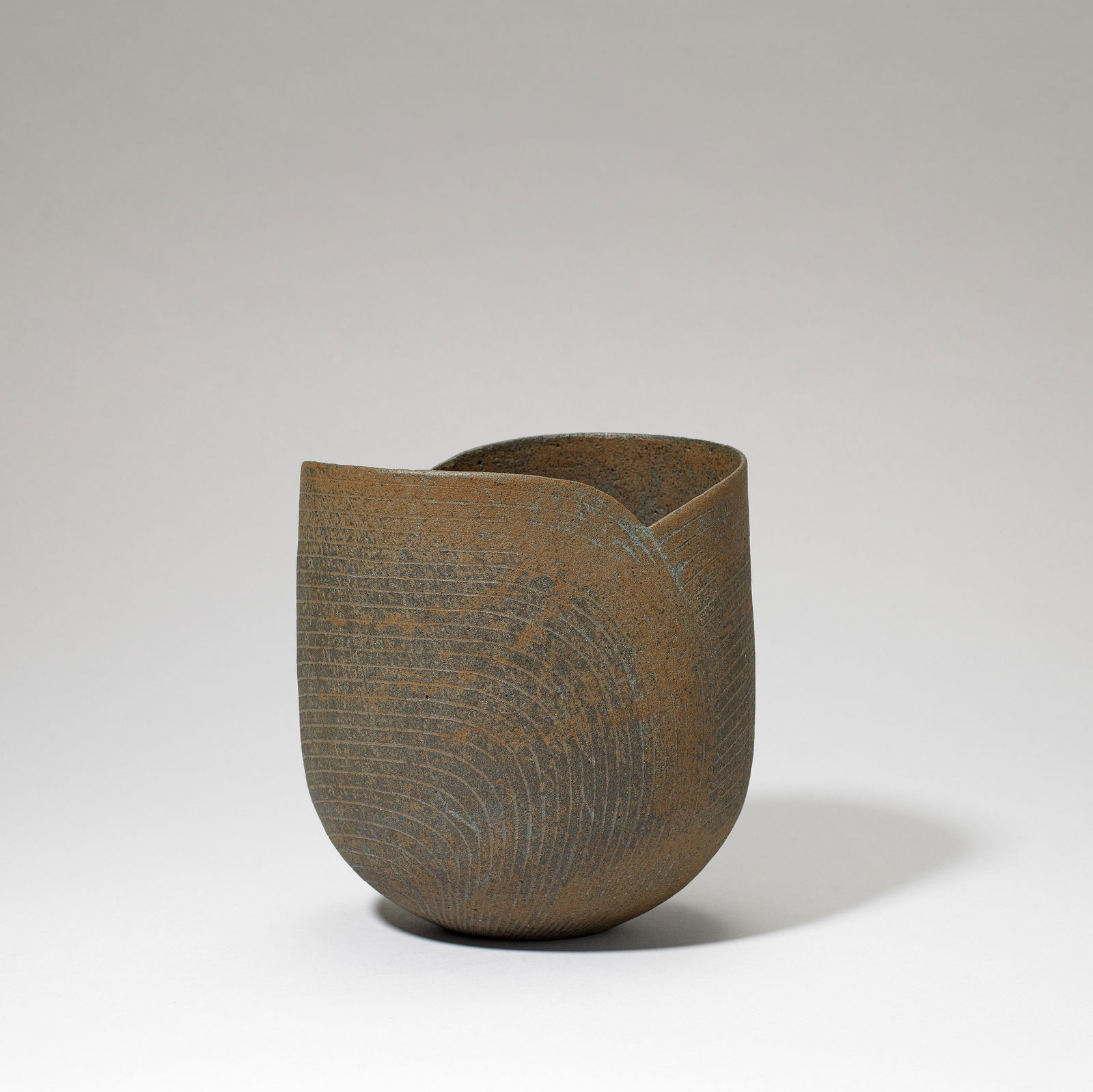 John Ward Vessel, circa 1985: John Ward Vessel, circa 1985 Stoneware, mottled brown glazes, incised linear decoration following the contours of the curved cut rim. 17.5cm high Impressed with artist's seal. Footnotes: Provenance Pe