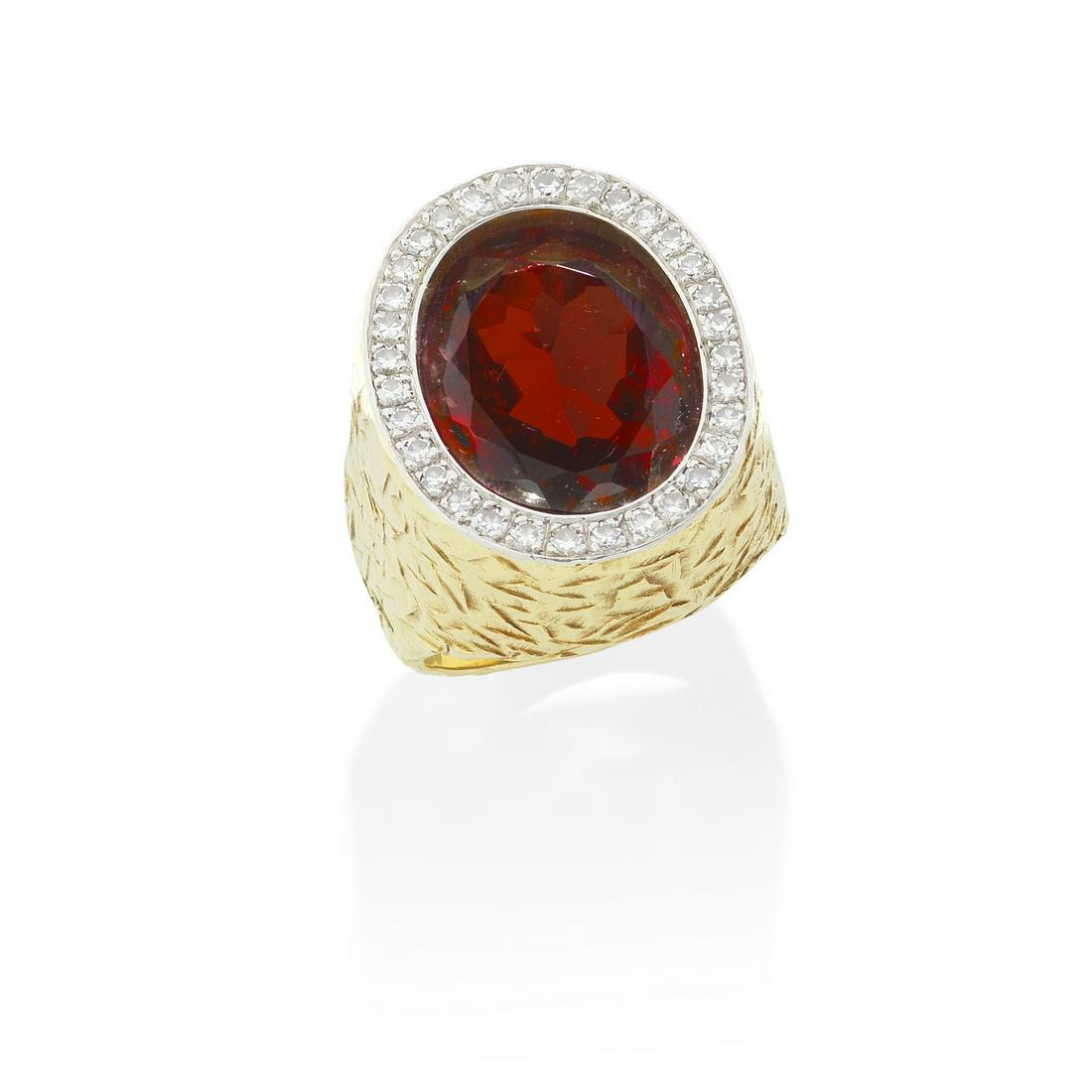 ANDREW GRIMA: GARNET AND DIAMOND RING, 1972: ANDREW GRIMA: GARNET AND DIAMOND RING, 1972 The oval-cut garnet, within a brilliant-cut diamond surround, mounted in textured 18 carat gold, signed Grima, AGLtd, UK hallmark, diamonds approximately 0