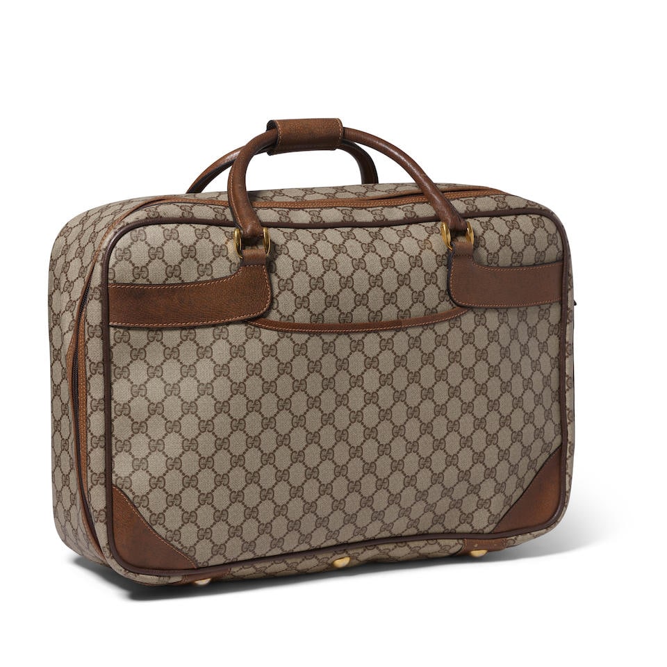 GUCCI: GG SUPREME WEEKENDER: GUCCI: GG SUPREME WEEKENDER • Brown Coated Canvas GG Logo Exterior • Brass Tone Hardware • Zip Closure • Canvas Lined Interior with Luggage Straps • Protective Feet at Ba