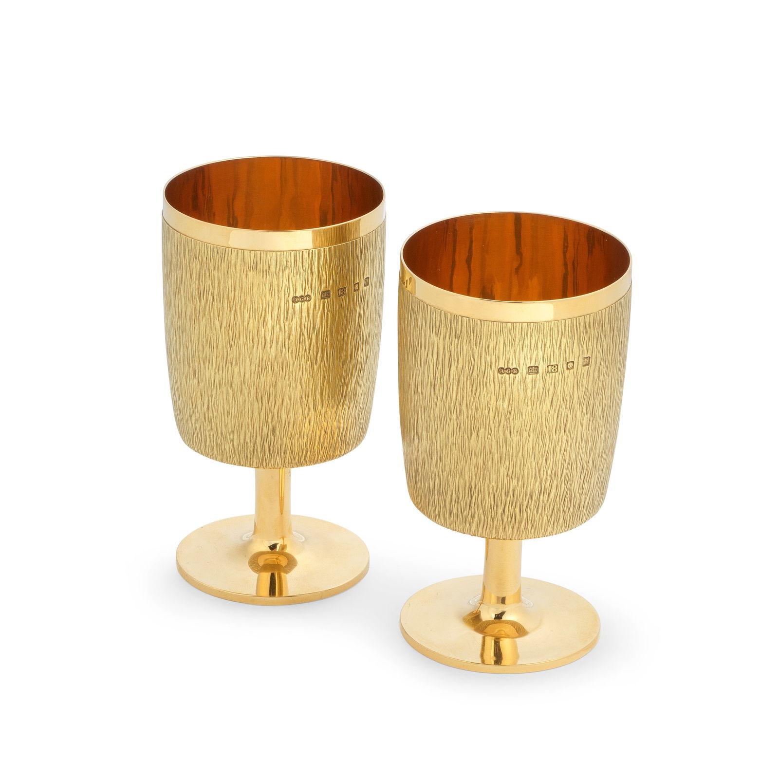 GERALD BENNEY: a pair of 18 carat gold goblets London 1968, stamped to the underside 'Gerald Ben...: GERALD BENNEY: a pair of 18 carat gold goblets London 1968, stamped to the underside 'Gerald Benney London' Cylindrical sides with bark effect textured surface, plain ploshed stems and circular bases