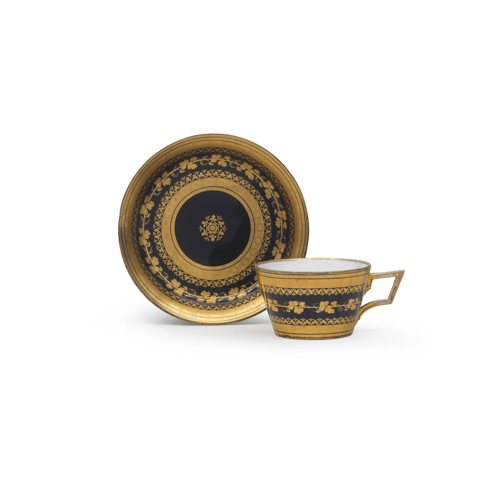 A Vienna dark-blue ground cup and saucer, circa 1800: A Vienna dark-blue ground cup and saucer, circa 1800 Decorated with elaborate gilding with tooled foliate bands and classical borders, the cup: 5.2cm high; the saucer: 14cm diam., shield marks in unde