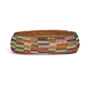 A Pomo beaded basket: A Pomo beaded basket Of oval form, interwoven with multicolored beads. height 2in, width 6 1/2in, depth 3 1/4in Footnotes: Illustrated The American Indian Artifact Catalog & Price Guide, Fall 1974, Vo