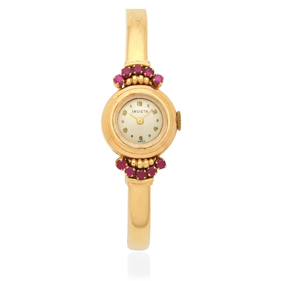 Invicta. A lady's 18K gold manual wind bangle watch with synthetic rubies Circa 1960: Invicta. A lady's 18K gold manual wind bangle watch with synthetic rubies Date: Circa 1960 Movement: 17-jewel manual wind Dial: Silvered Case: Brushed and polished round, synthetic ruby set lugs Strap
