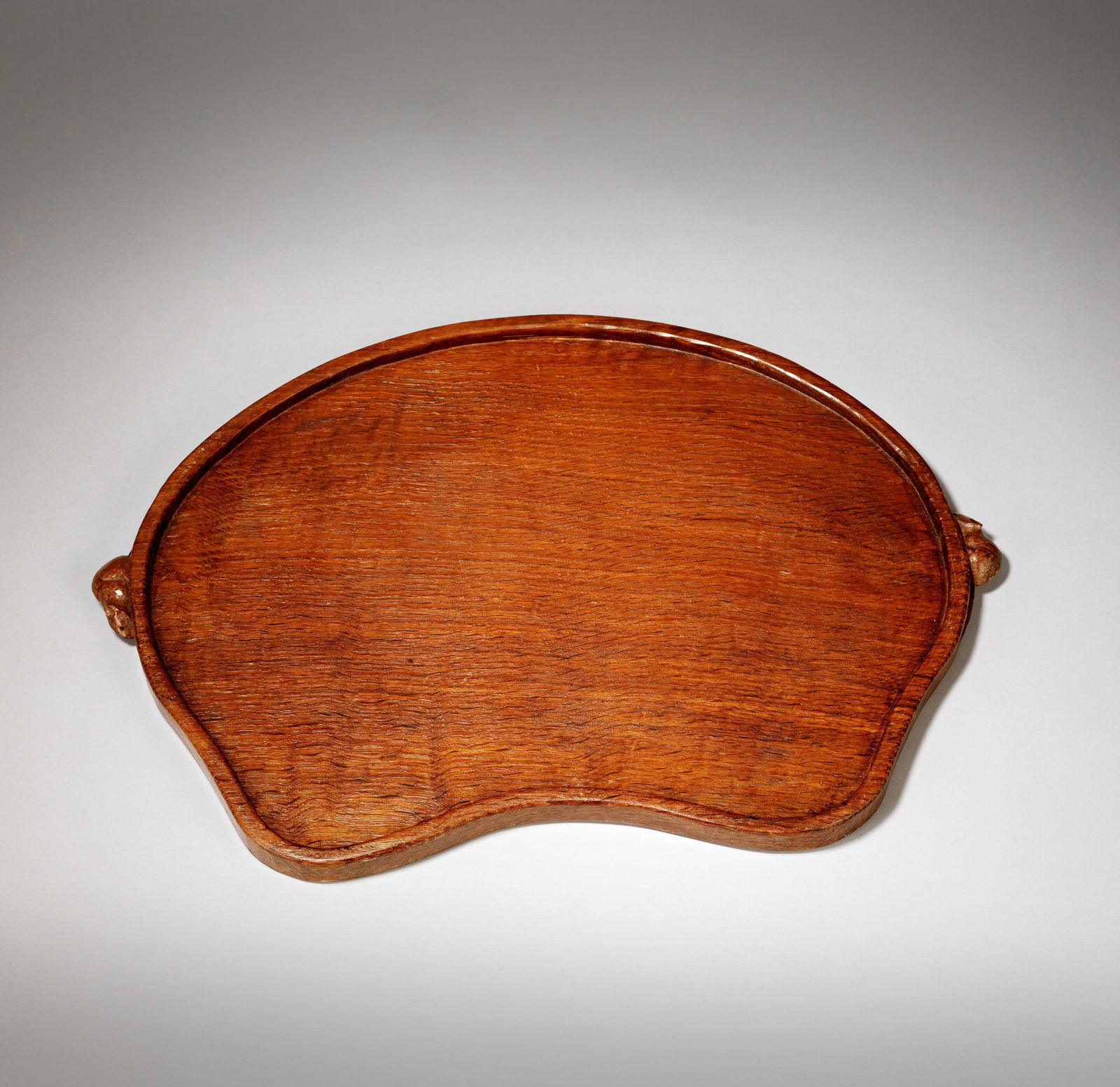 ROBERT 'MOUSEMAN' THOMPSON (BRITISH, 1876-1955) OF KILBURN Tray, second half 20th century: ROBERT 'MOUSEMAN' THOMPSON (BRITISH, 1876-1955) OF KILBURNTray, second half 20th centuryOak, kidney shaped with tooled surface and raised lip, dark patination, carved on the edge with two plump mice,