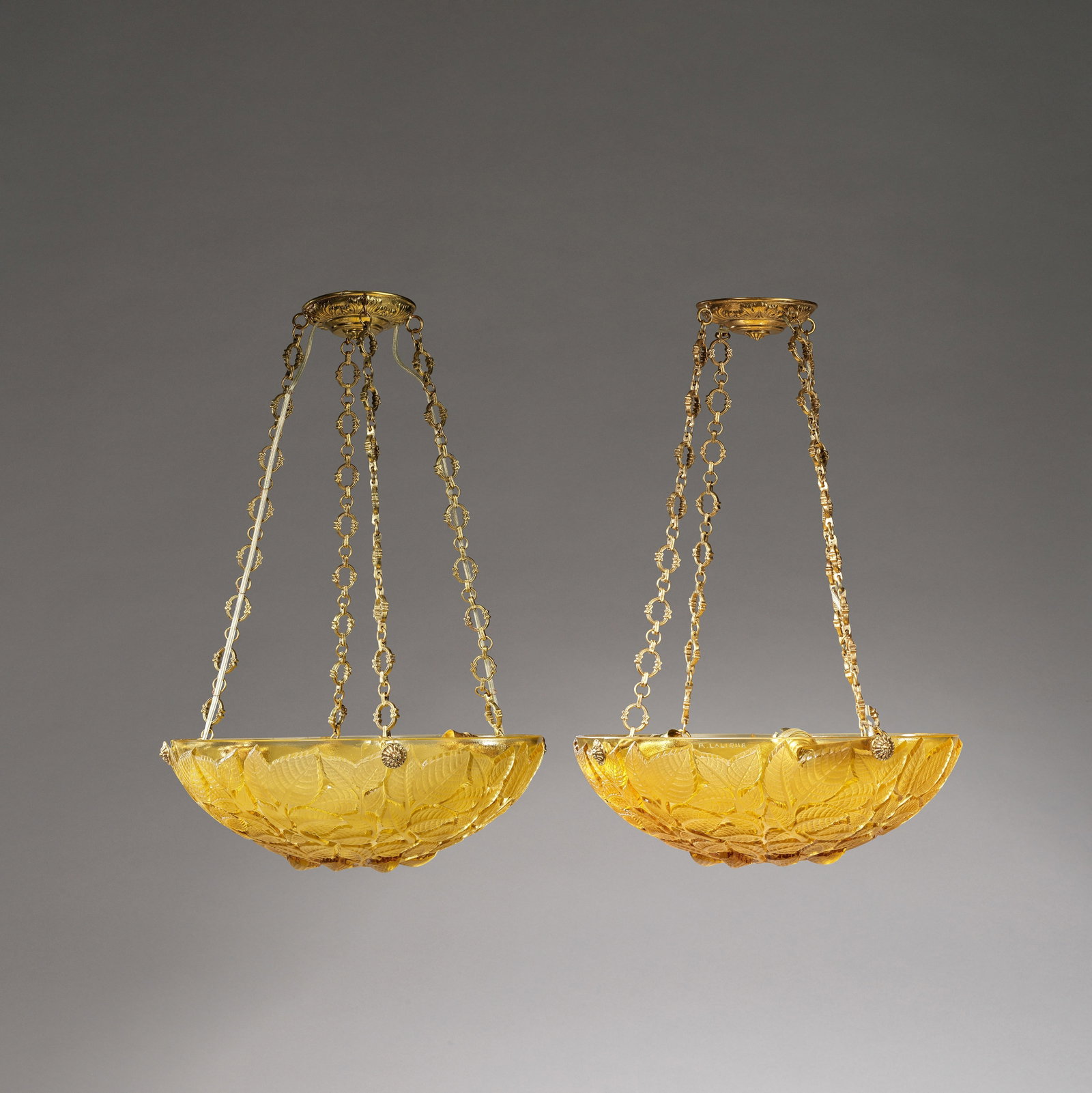 RENÉ LALIQUE (FRENCH, 1860-1945) Two 'Charmes' plafonniers vasque, designed 1924: RENÉ LALIQUE (FRENCH, 1860-1945)Two 'Charmes' plafonniers vasque, designed 1924Amber glass, frosted and polished, with suspension chains and fittings. Each: 35 cm diameterEach moulded R.LALIQUE t