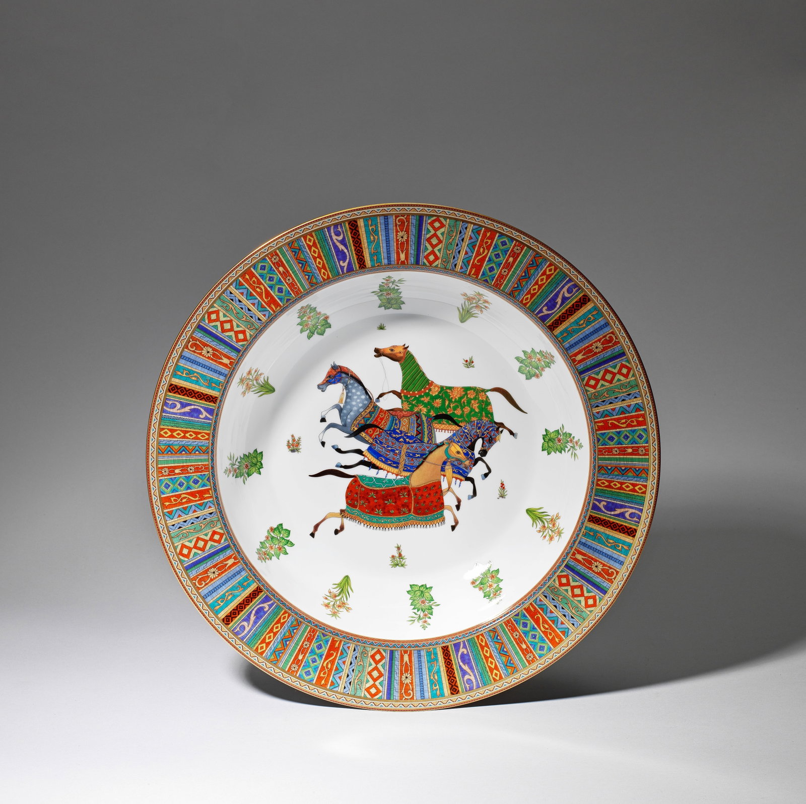 HERMÉS Large 'Cheval d'Orient' serving dish, 21st century: HERMÉSLarge 'Cheval d'Orient' serving dish, 21st centuryPorcelain, with vibrant polychrome glazes and gilt. Decoration and forms inspired by horses and elements of horse harnesses.42.3 cm diamete