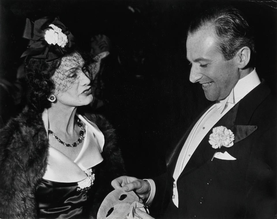 John Phillips (1914-1996);: John Phillips (1914-1996) A black and white photograph of Coco Chanel with Cecil Beaton, 1937 With later photographer's ink-stamp credit to reverse, dated 1976 27.5 x 35cm (10 13/16 x 13 3/4in) Footn