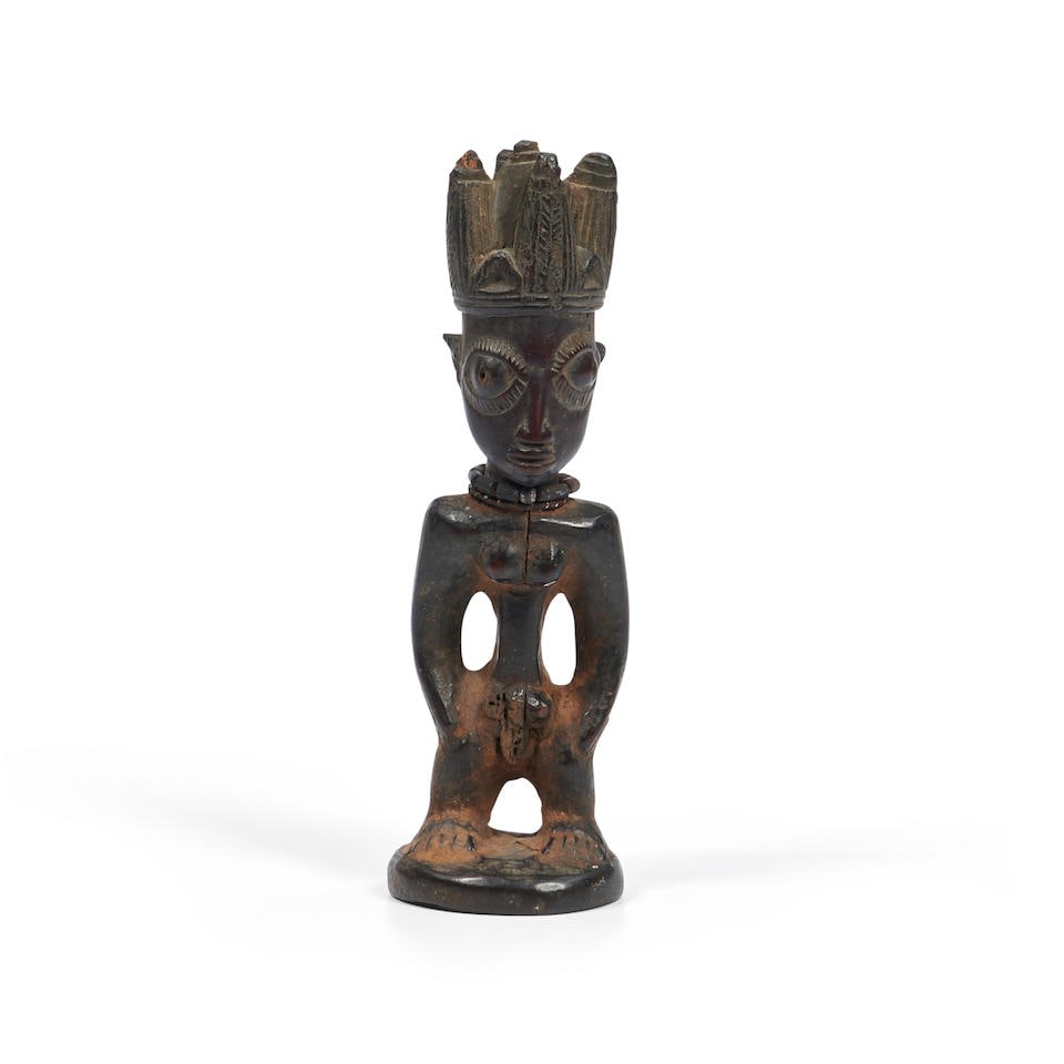A male Yoruba Ibeji figure ht. 10 1/2 in.: A male Yoruba Ibeji figure Nigeria, standing on a circular base, with raised feet, legs set apart with the arms detached from the body, and hands on thighs, straight shoulders beneath the elongated, o