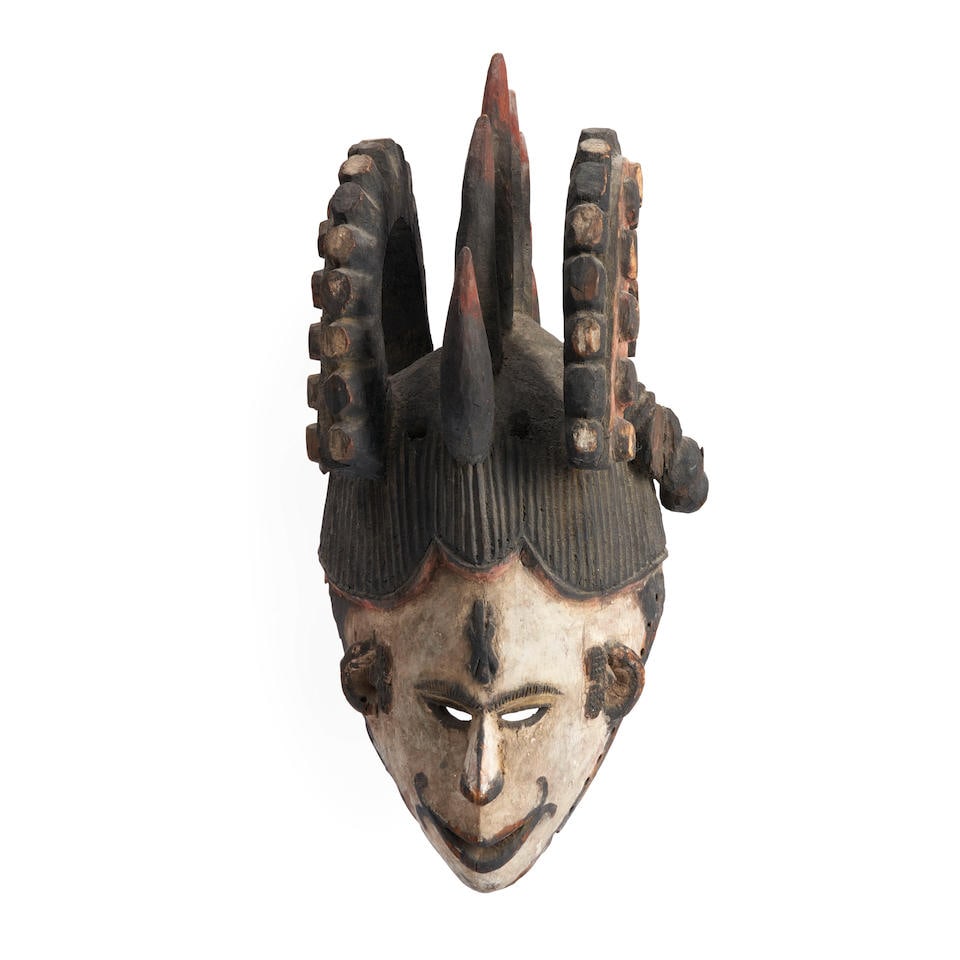 An Ibo Maiden Spirit helmet mask Agbogho Mmuo ht. 16 1/2 in.: An Ibo Maiden Spirit helmet mask Agbogho Mmuo Nigeria, the hollowed-out helmet form pierced around the rim for attachment of a cloth head covering, the narrow angular face with pointed chin and open m