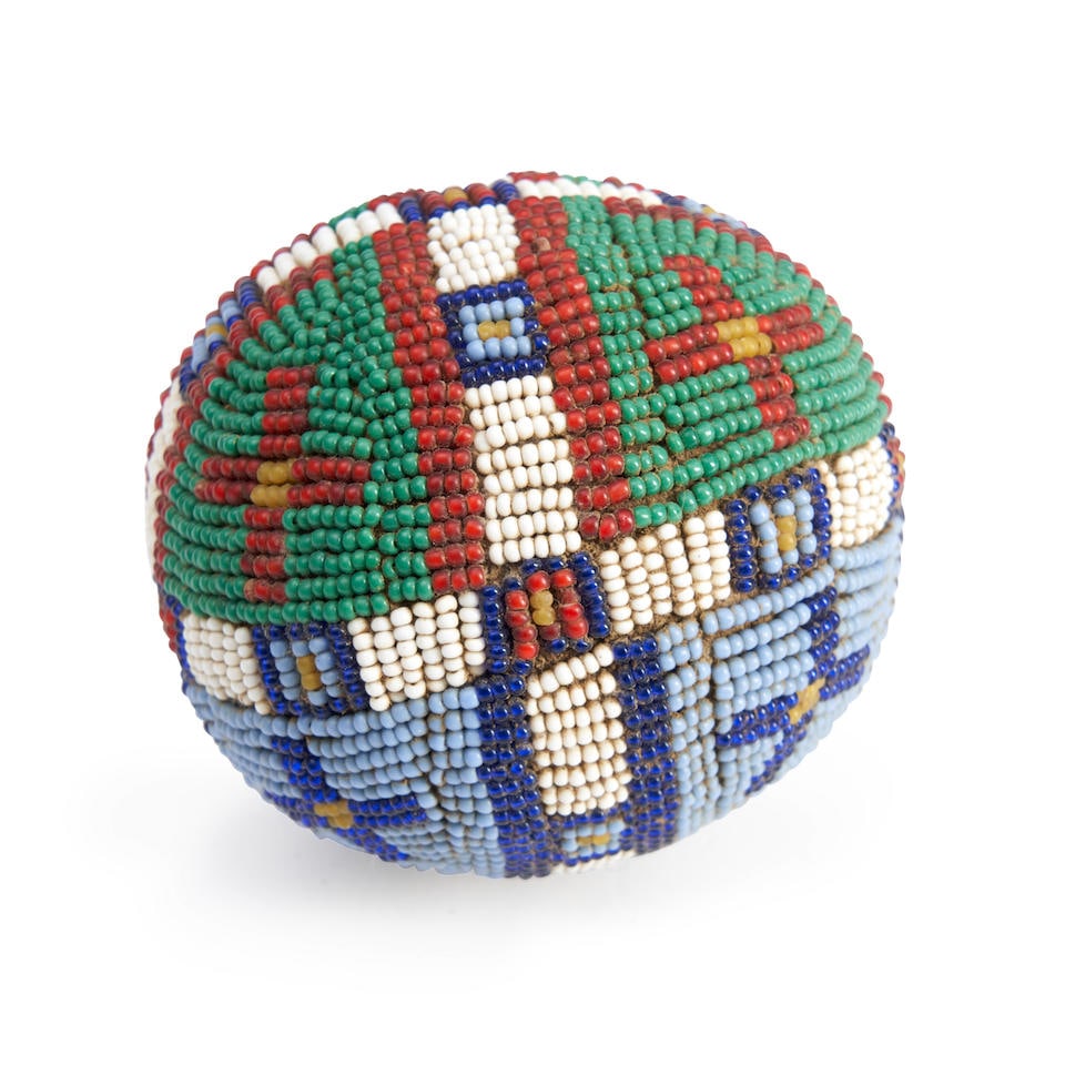 A Plains beaded hide ball wd. 2 5/8 in.: A Plains beaded hide ball Decorated in multicolored geometric designs with cross and bands, primarily on blue and green beaded grounds. wd. 2 5/8 in. For further information on this lot please visit B