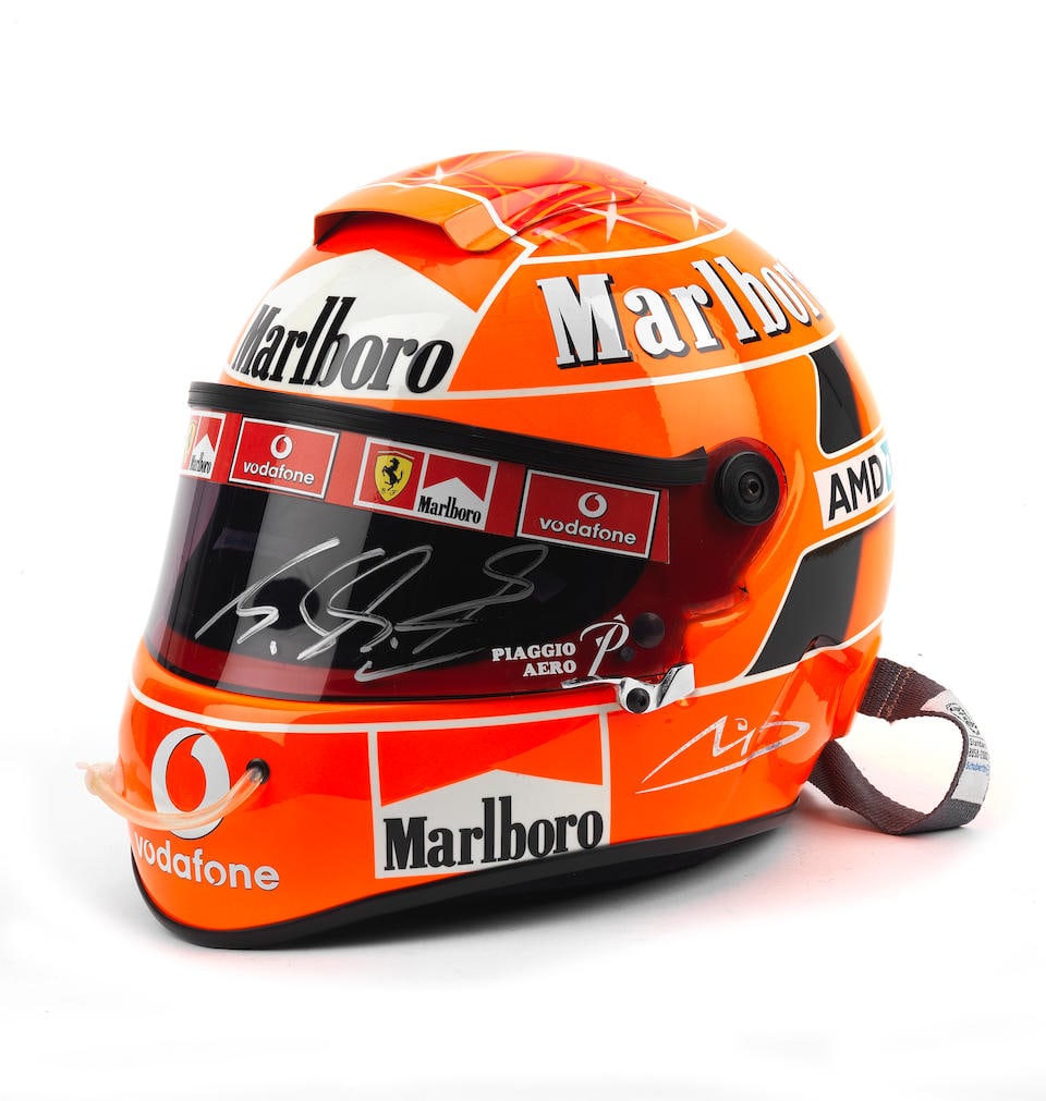 A signed Replica Michael Schumacher 2006 helmet by Schuberth,: A signed Replica Michael Schumacher 2006 helmet by Schuberth, in bright red design with sponsors logos, signed to the visor in silver pen, with drinks tube attached to front, and straps to rear. For f
