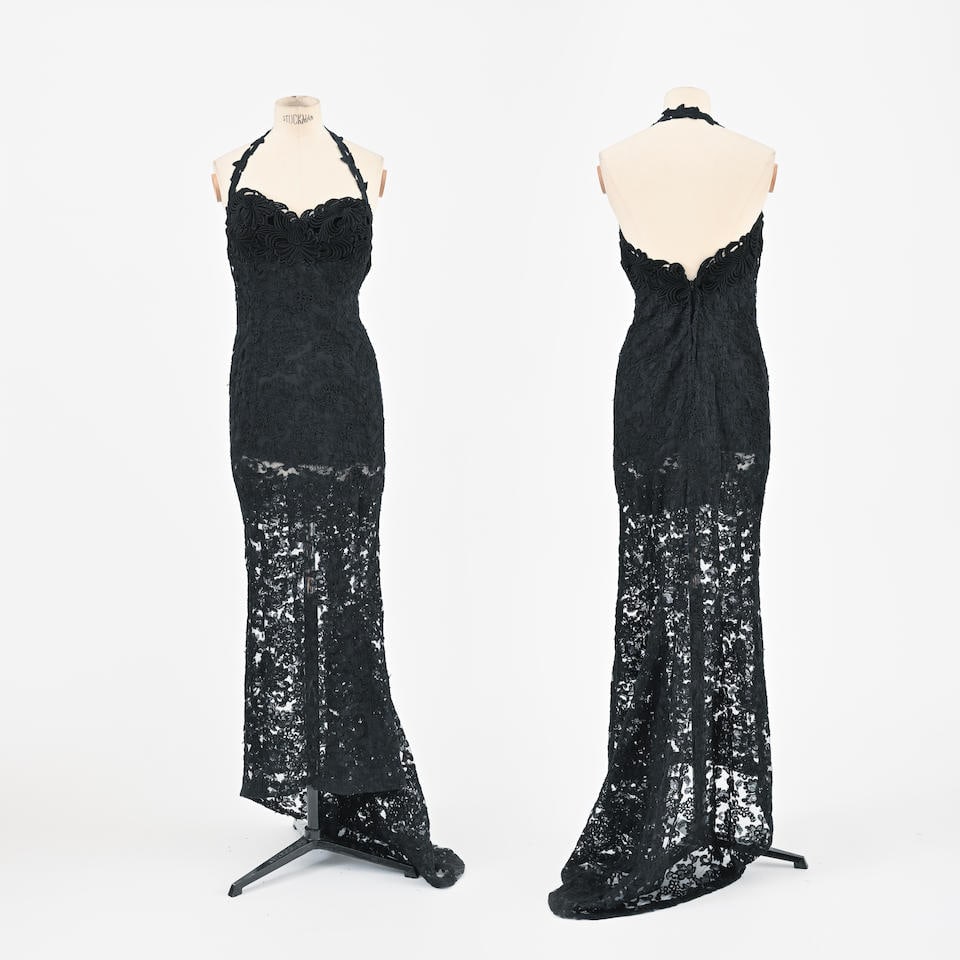 Fernando SANCHEZ. Robe de soirée en dentelle mécanique noire.: Fernando SANCHEZ. Robe de soirée en dentelle mécanique noire. Doublure jusqu'au hanches, bretelle passant dans le cou. Taille indiquée: 6. Condition d'état: A. Footnotes: Black mec