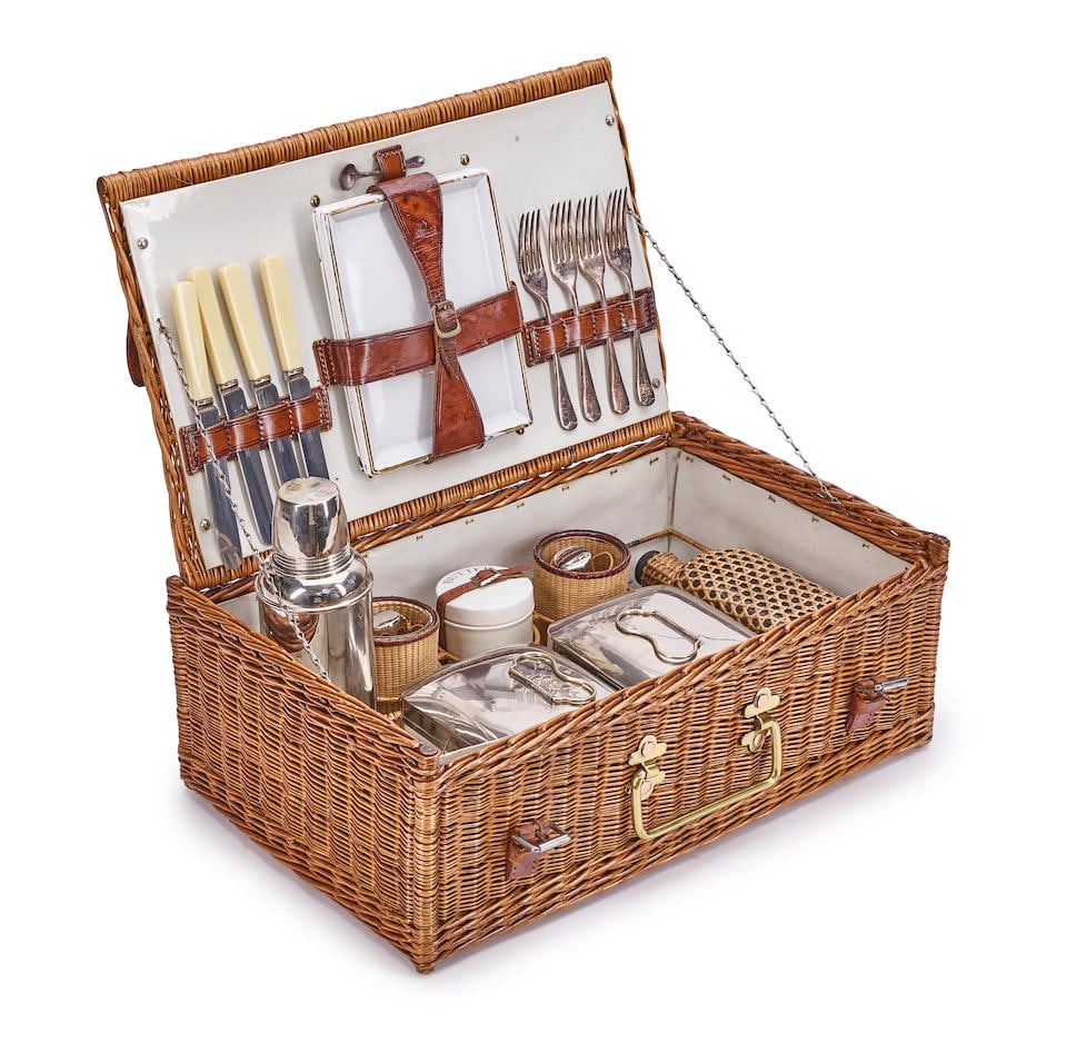 A JC VICKERY WICKER-CASED PICNIC SET FOR FOURLondon, 1908-1913: A JC VICKERY WICKER-CASED PICNIC SET FOR FOUR London, 1908-1913 The wicker case with brass handle and leather straps, opening to reveal a fitted interior with a metal Thermos flask, two silver lidded