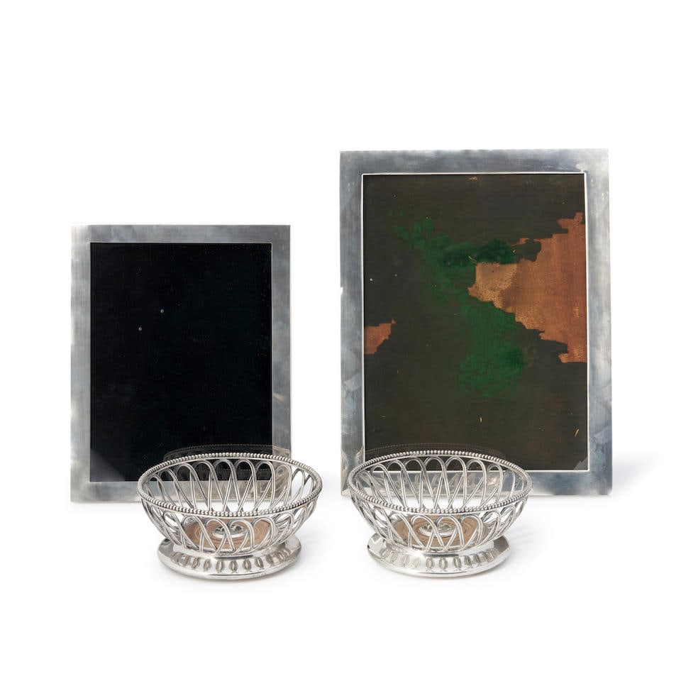 PAIR OF ELKINGTON SILVERPLATE WIRE BOTTLE BASKETS AND TWO STERLING SILVER PICTURE FRAMES: PAIR OF ELKINGTON SILVERPLATE WIRE BOTTLE BASKETS AND TWO STERLING SILVER PICTURE FRAMES the pierced baskets with beaded rim, dia. 6 1/2; one frame Tiffany & Co., ht. 10 3/4; the other I.N. Deitsch,