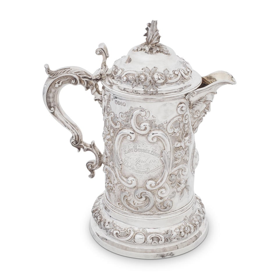 A Victorian large silver lidded jug Thomas Smily, London 1862: A Victorian large silver lidded jug Thomas Smily, London 1862 Tall cylindrical form embossed and chased in high relief with trailing flowers, acanthus and scrolls over a stippled ground, scroll carto
