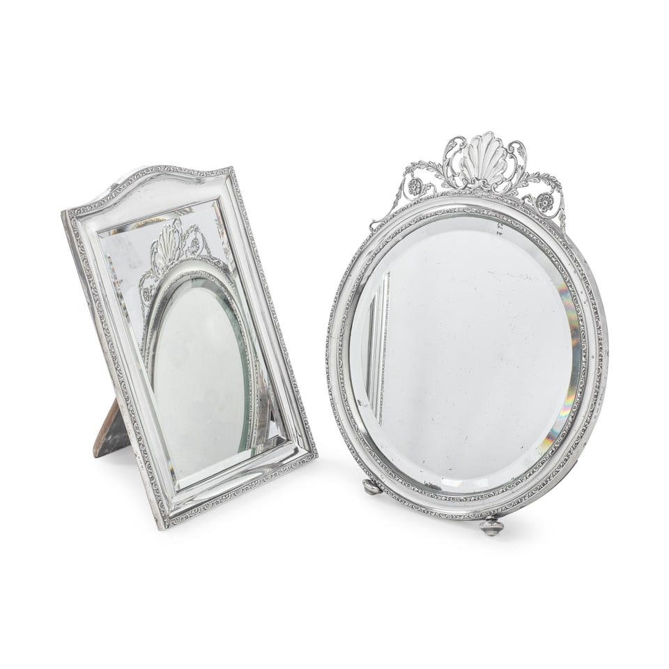 Two silver table mirrors both Henry Matthews, Birmingham 1913 and Birmingham 1909 (2): Two silver table mirrors both Henry Matthews, Birmingham 1913 and Birmingham 1909 The first, circular, the concave border between two narrow scroll rims, shell and foliate scroll surmount, on bun fee