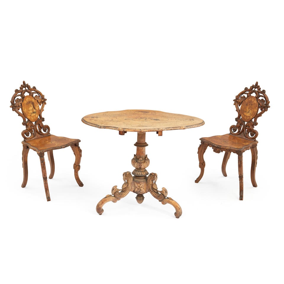 SWISS MARQUETRY-INLAID AND CARVED WALNUT TABLE AND TWO CHAIRS: SWISS MARQUETRY-INLAID AND CARVED WALNUT TABLE AND TWO CHAIRS Early 20th century, inlaid with fruitwood scenes of deer, all carved in high relief with foliage, table ht. 28 1/2, wd. 36 1/2, dp. 27, ch