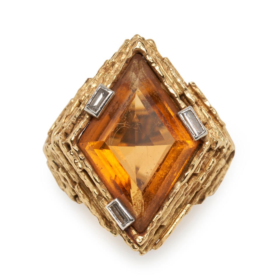 ANDREW GRIMA: AN 18K GOLD, CITRINE, AND DIAMOND RING, CIRCA 1968: ANDREW GRIMA: AN 18K GOLD, CITRINE, AND DIAMOND RING, CIRCA 1968 Centering a fancy-cut citrine measuring approximately 21.70 14.60 x 7.50 mm, set in a heavily textured gold mount, with baguette-cut di