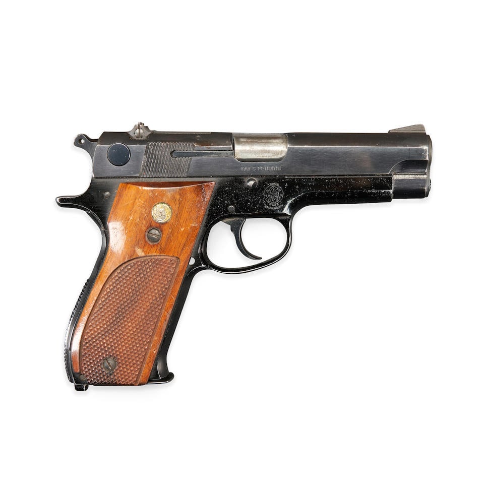 A SMITH & WESSON MODEL 39-2 SEMI AUTOMATIC PISTOL, Modern handgun: A SMITH & WESSON MODEL 39-2 SEMI AUTOMATIC PISTOL, 1970s-early 80s. Serial number A156285, 9mm caliber, blackened alloy slide and frame with proper roller engraved markings, checkered walnut grips wit