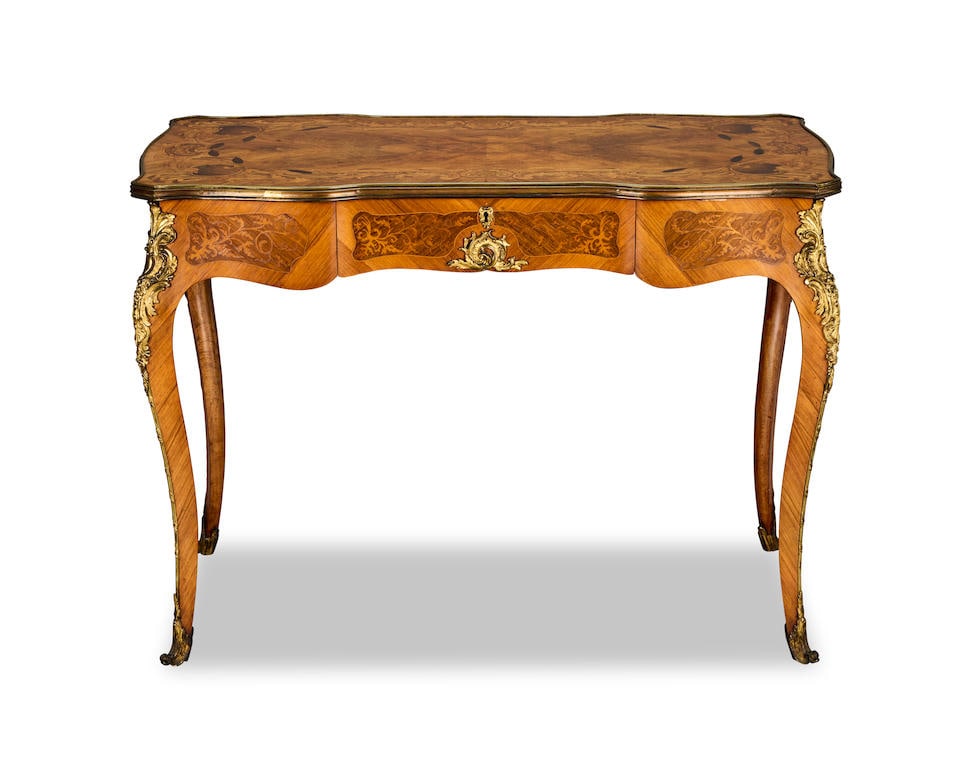 An early Victorian ormolu mounted walnut, tulipwood, palmwood and marquetry writing table 1840-1...: An early Victorian ormolu mounted walnut, tulipwood, palmwood and marquetry writing table 1840-1845, in the manner of Edward Holmes Baldock The shaped quarter veneered and cartouche inlaid top with a