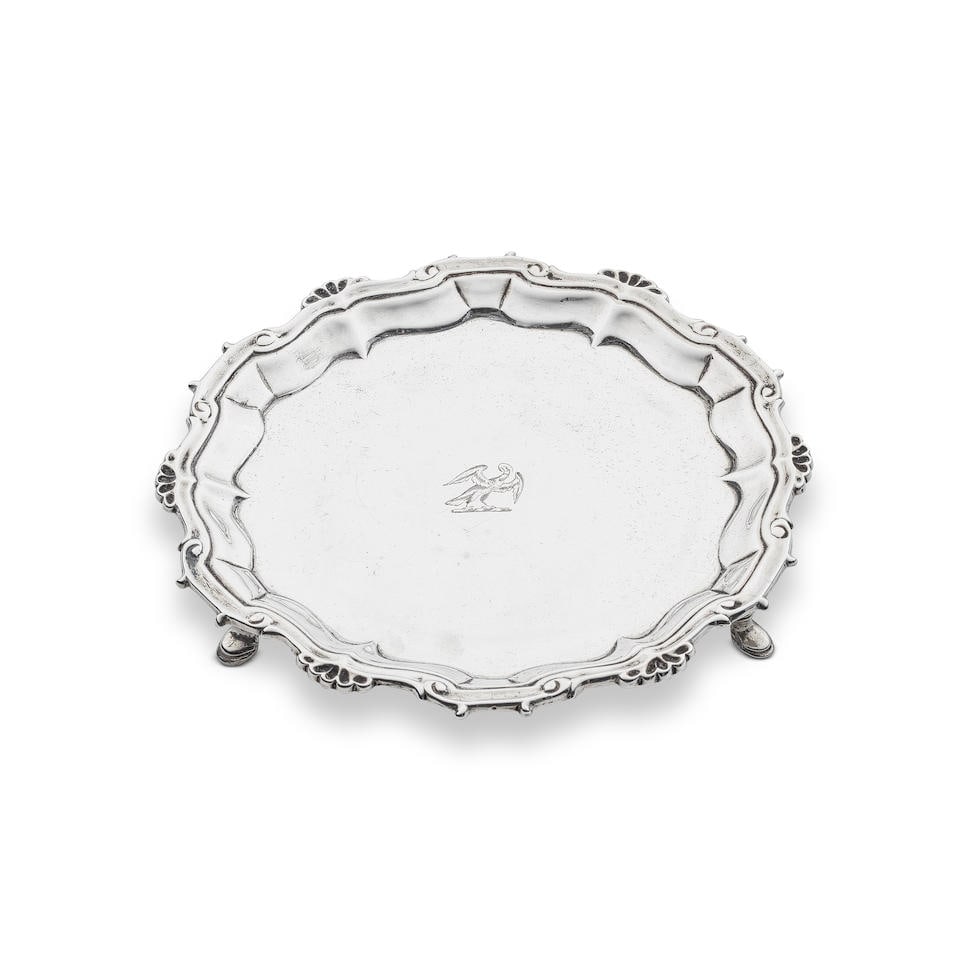 A small George II silver salver William & Robert Peaston, London 1757: A small George II silver salver William & Robert Peaston, London 1757 On three stepped feet with shaped foliate rim, engraved with Drummond family Goshawk crest and motto, diameter 15.75cm, weight 7.