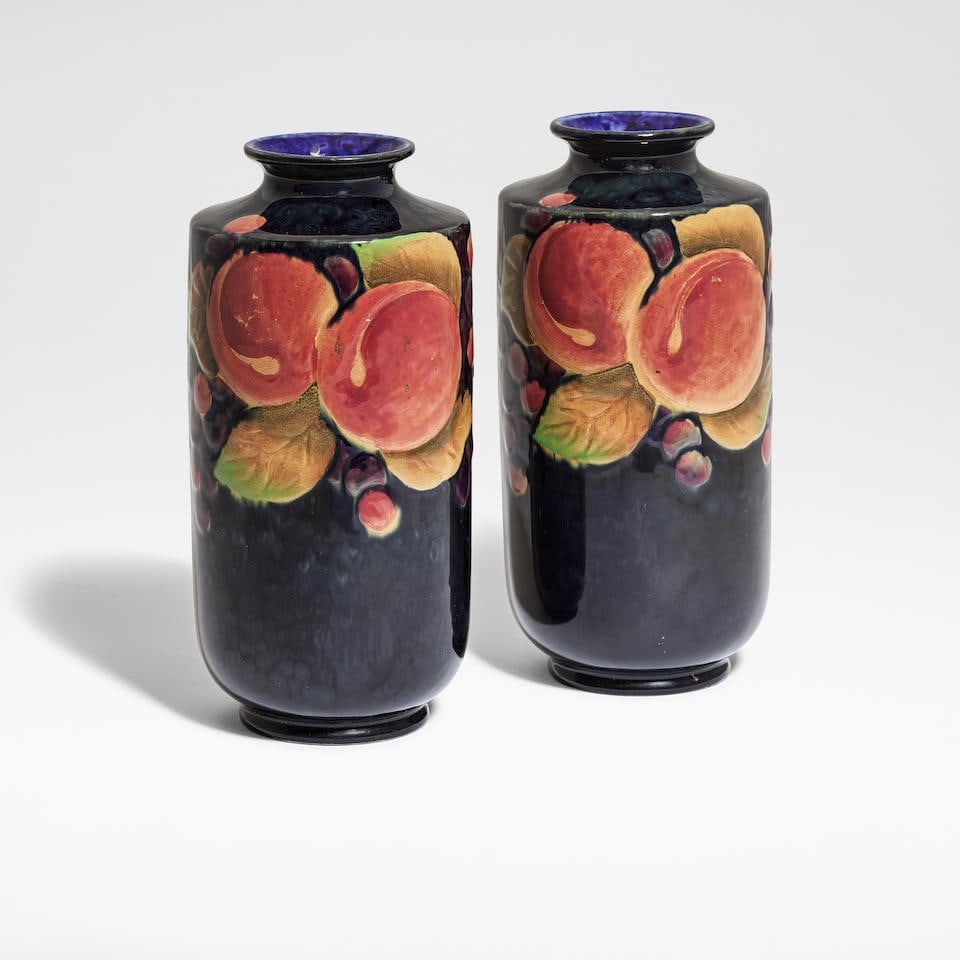 Attributed to Charlotte Rhead for Shelley Potteries 'Pomegranate', pair of vases, circa 1928: Attributed to Charlotte Rhead for Shelley Potteries 'Pomegranate', pair of vases, circa 1928 Glazed earthenware, decorated in bas-relief with fruit and foliage against a cobalt ground, of cylindrical