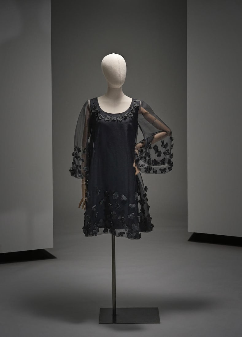 Jean Varon, collection Prêt-à-Porter, circa 1972. Robe de cocktail en cigaline noir.: Jean Varon, collection Prêt-à-Porter, circa 1972. Robe de cocktail en cigaline noir. De forme évasée, large décolleté rond, manches longues pagodes; l'ensemble à d&#