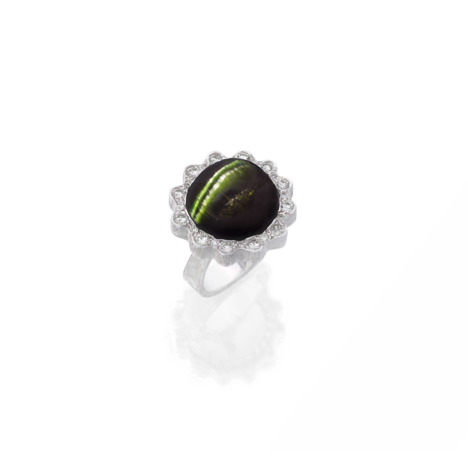 GRIMA: CAT'S EYE TOURMALINE AND DIAMOND RING, CIRCA 1986: GRIMA: CAT'S EYE TOURMALINE AND DIAMOND RING, CIRCA 1986 The circular cabochon cat's eye tourmaline, within a scalloped surround of brilliant-cut diamonds, the gallery and geometric band with textured
