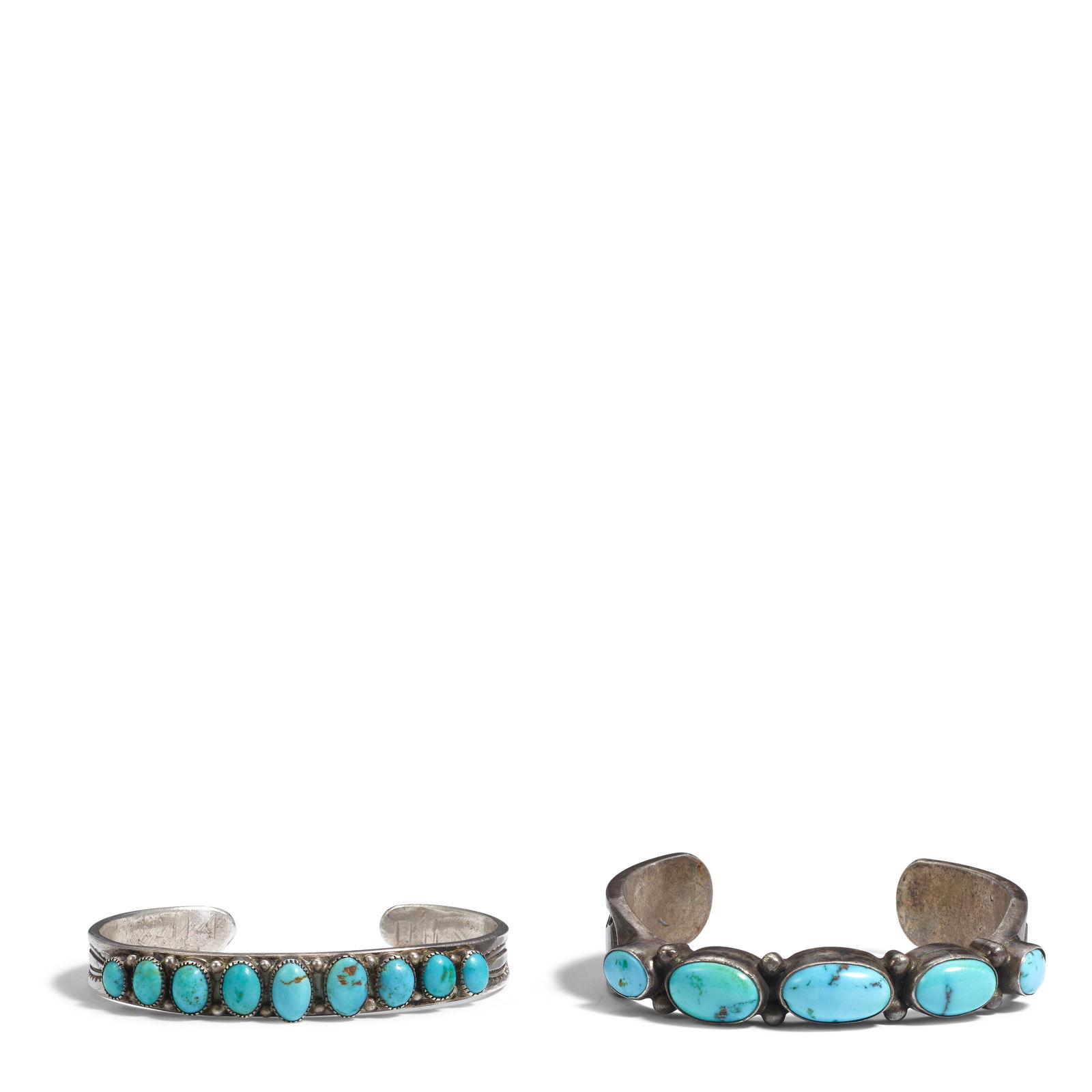 Two Diné (Navajo) silver cuff bracelets: Two Diné (Navajo) silver cuff bracelets One with a row of five graduated oval turquoise cabochons set on a thick conforming band, the terminals heavily stamped; and a narrow cuff with nine gradua