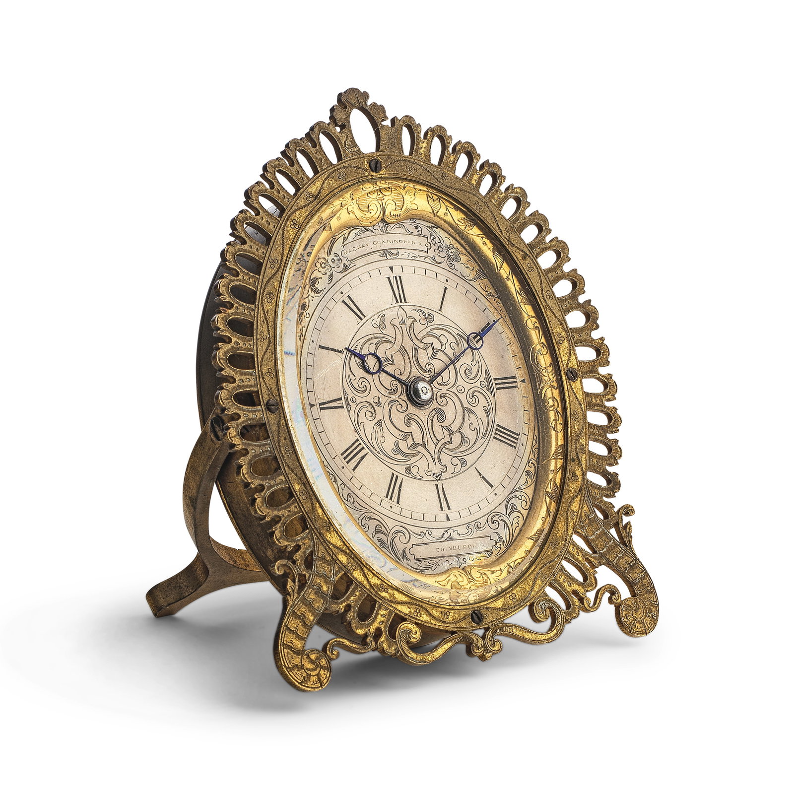 A mid 19th century strut timepiece in the style of Thomas Cole Mackay Cuunningham & Co Edinburgh: A mid 19th century strut timepiece in the style of Thomas Cole Mackay Cuunningham & Co Edinburgh The gilt brass oval case framed by a pierced edge and engraved to the deep band bove XII with a monogra